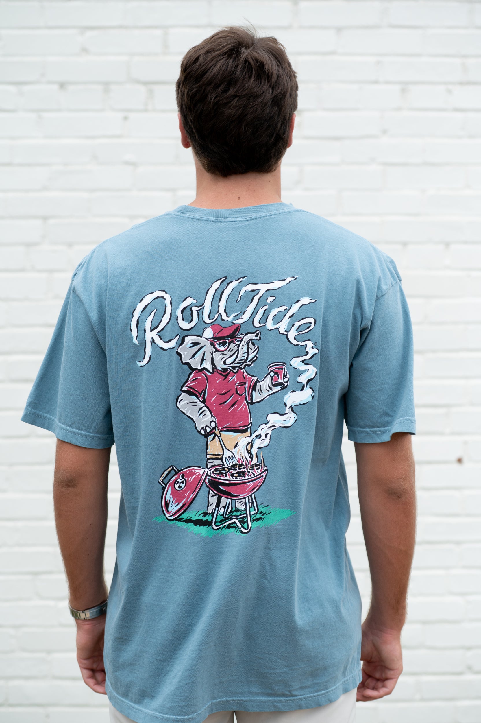 University of Alabama Blue T-Shirt with a drawing of Big Al grilling and the words “Roll Tide” written in the smoke