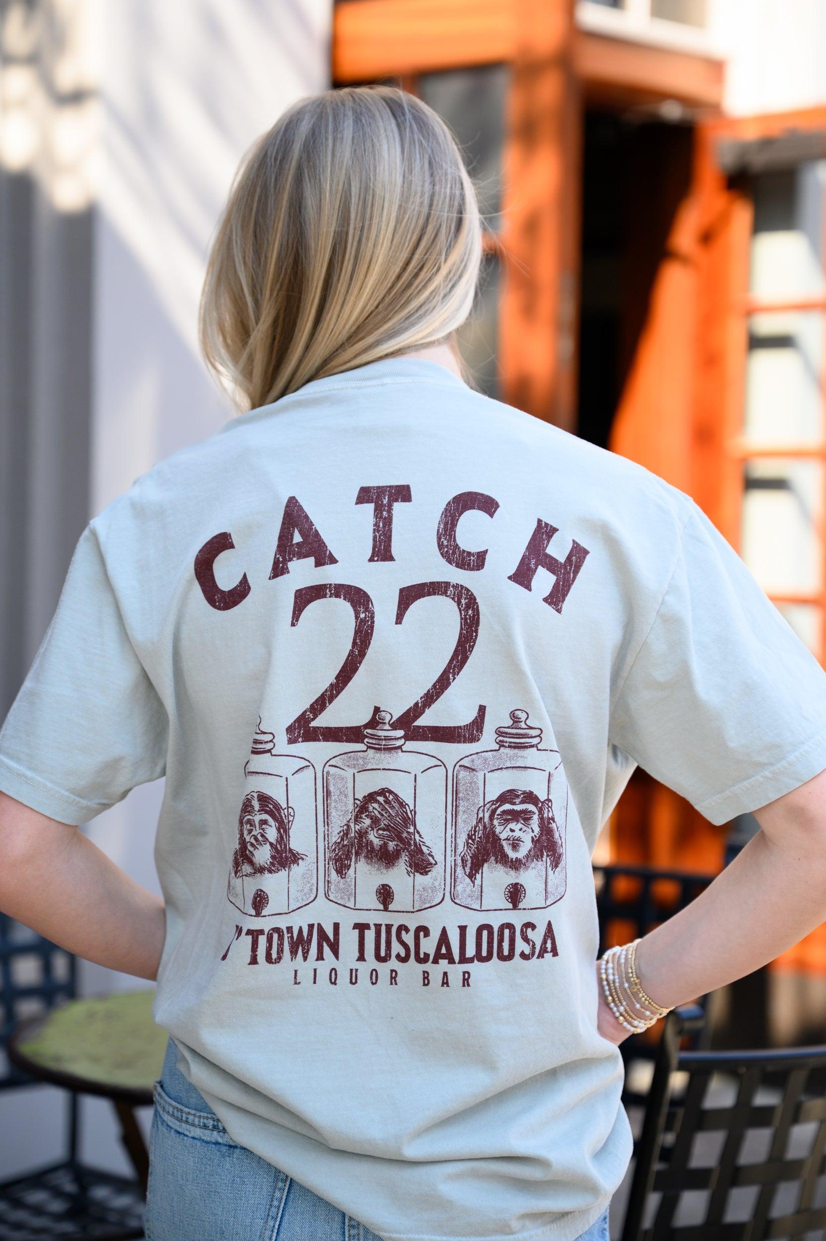 Catch 22 Dusty Green T-Shirt with Brown text “Catch 22” above an illustration of three monkeys in jars playing peekaboo above text “D’Town Tuscaloosa”