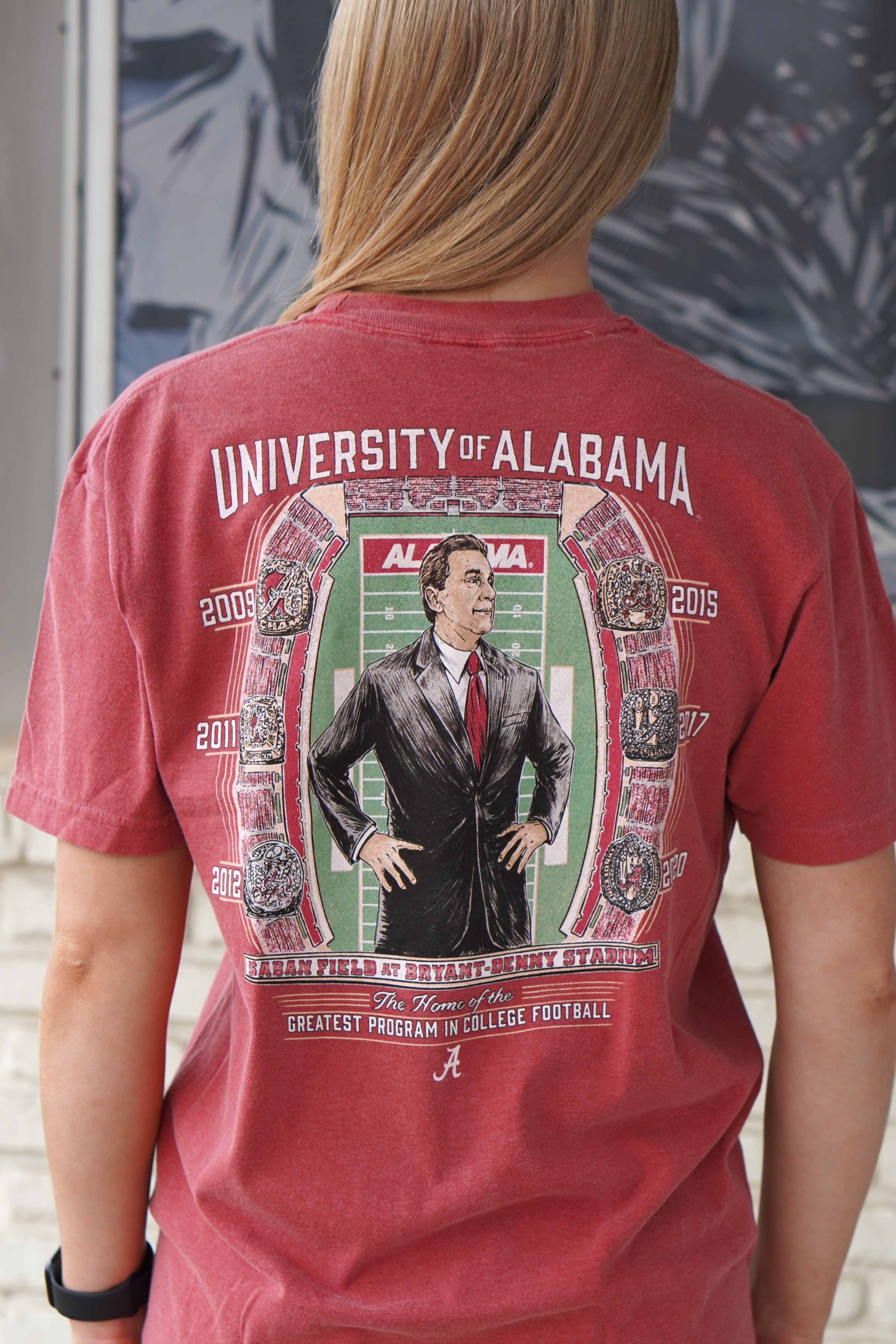 University of Alabama Champion Legacy at Saban Field Red Comfort Colors T-Shirt with an image of Nick Saban standing over Bryant-Denny Stadium surrounded by the years Alabama won the Football Championship