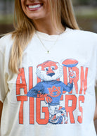 Auburn University Cream Chill Aubie Comfort Colors T-Shirt with Orange text "Auburn Tigers" and a graphic of Aubie leaning against the "G" of "Tigers"