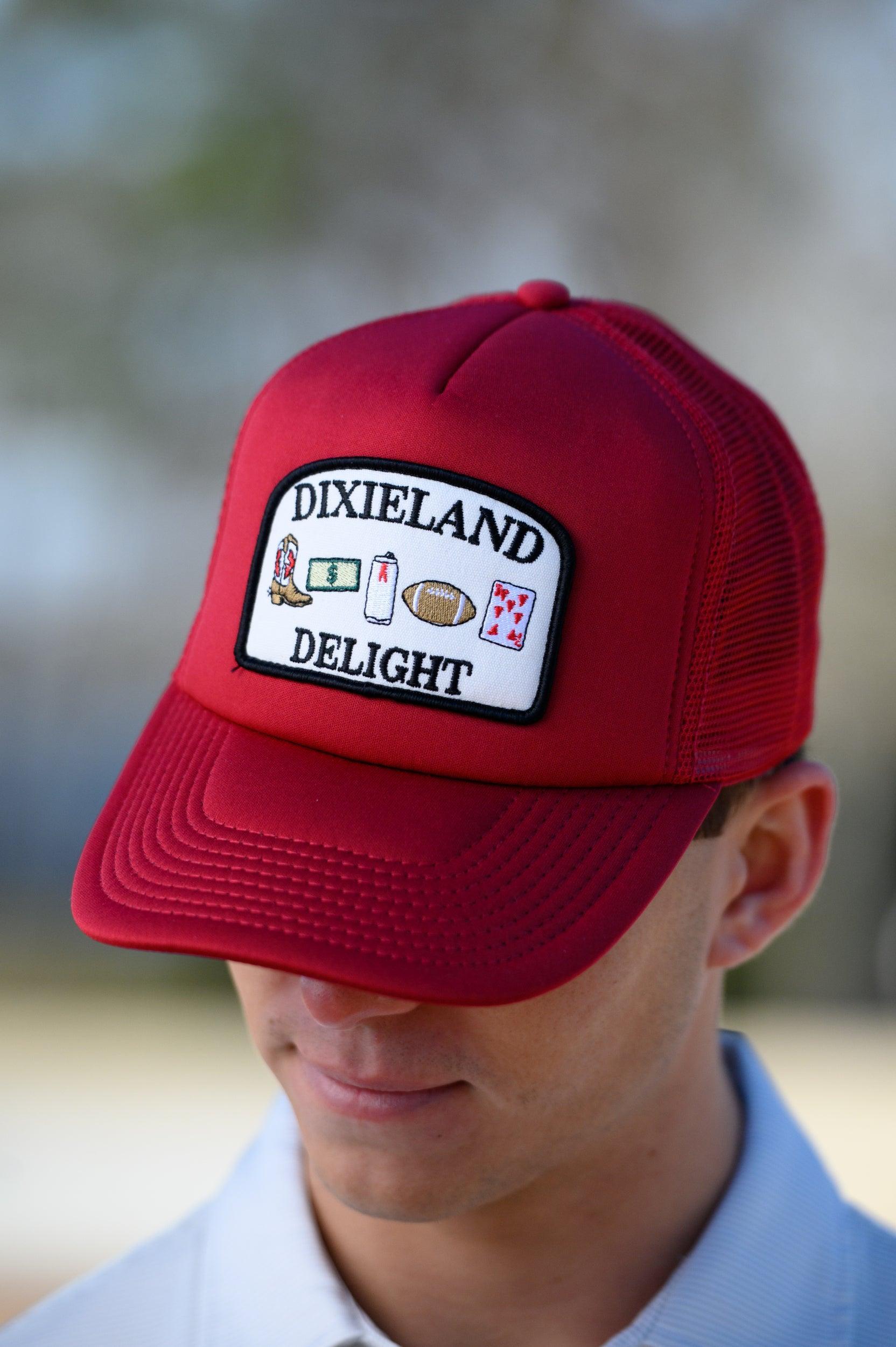 University of Alabama Red Trucker Hat with a patch featuring text “Dixieland” above and “Delight” below drawings of a cowboy boot, money, drink can, football, and playing card