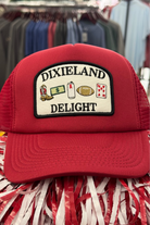 University of Alabama Red Trucker Hat with a patch featuring text “Dixieland” above and “Delight” below drawings of a cowboy boot, money, drink can, football, and playing card