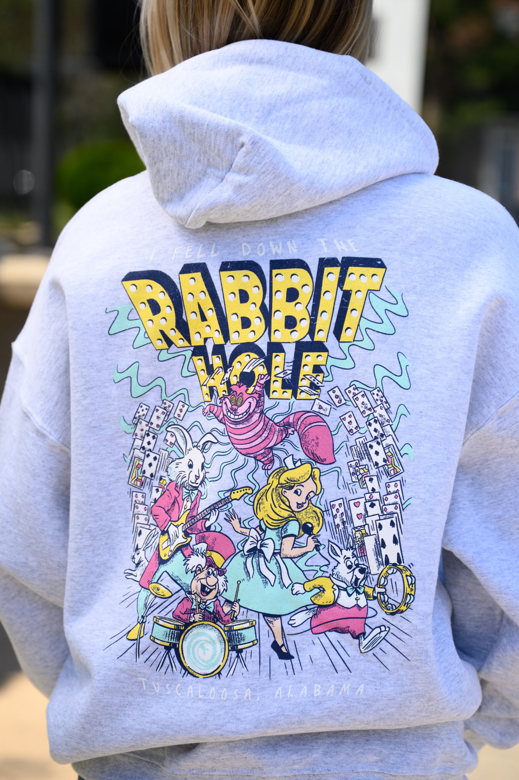 Grey Rabbit Hole Hoodie with marquee lights spelling "Rabbit Hole" lighting a band of Alice in Wonderland characters surrounded by playing cards