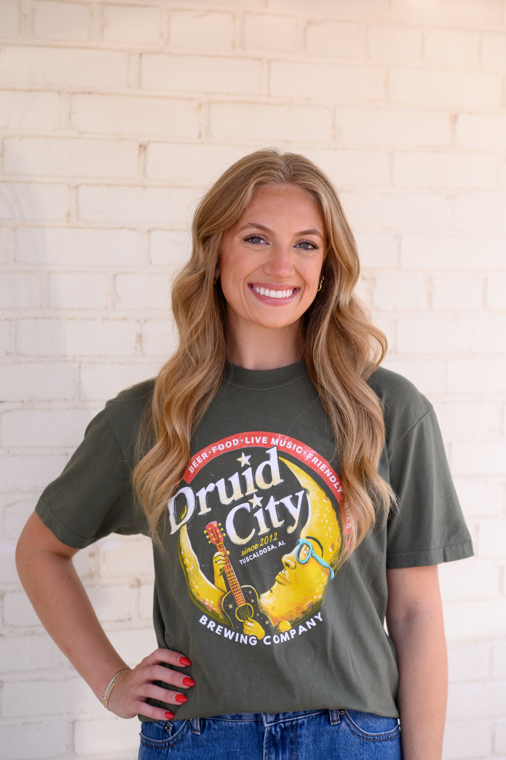 Druid City Brewing Company Olive Green Tee with text "Druid City" above a Crescent Moon wearing glasses and playing a guitar