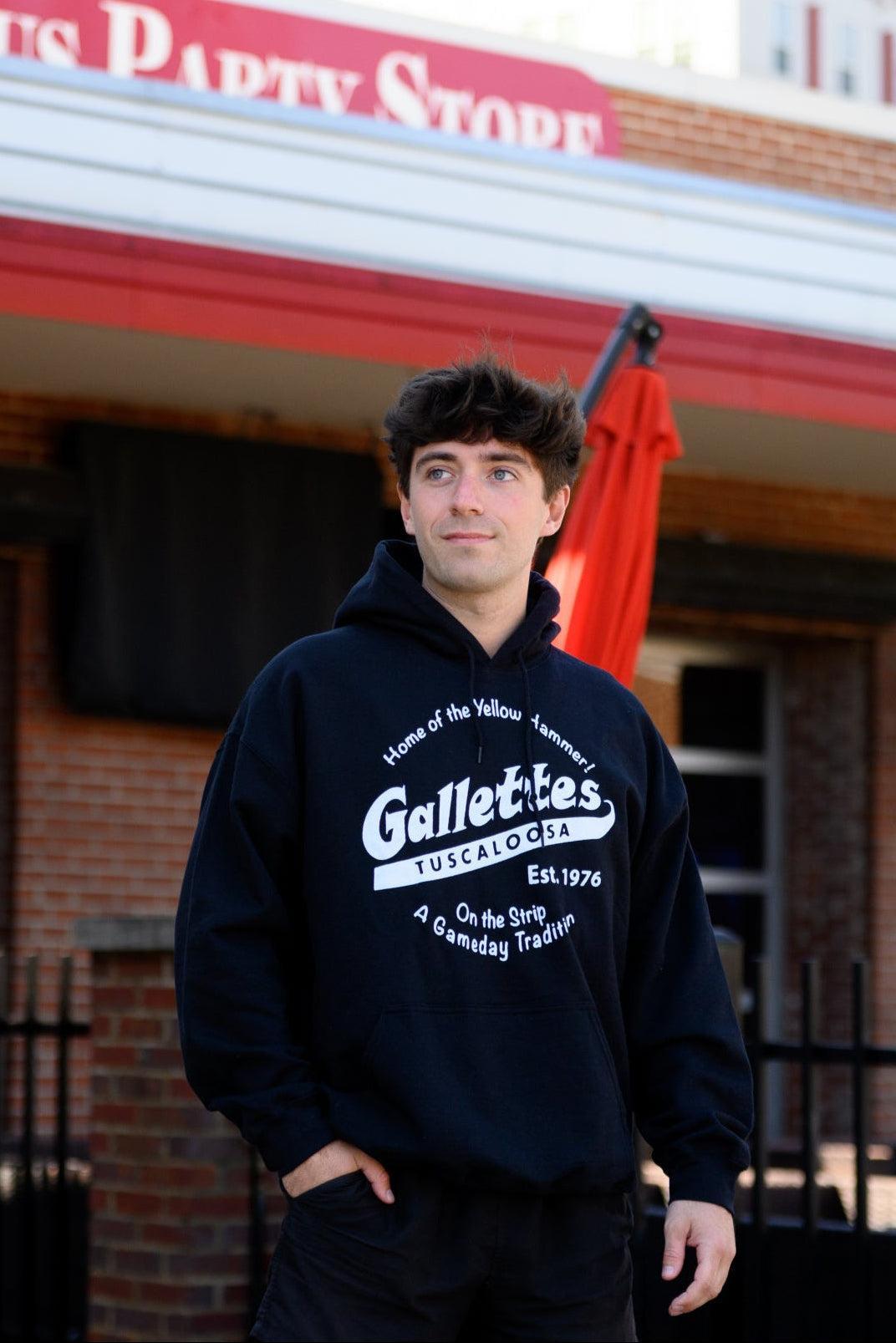 Gallettes Black Hoodie with a White Gallettes logo surrounded by White text "Home of the Yellow Hammer!" and "On the Strip- A Gameday Tradition"