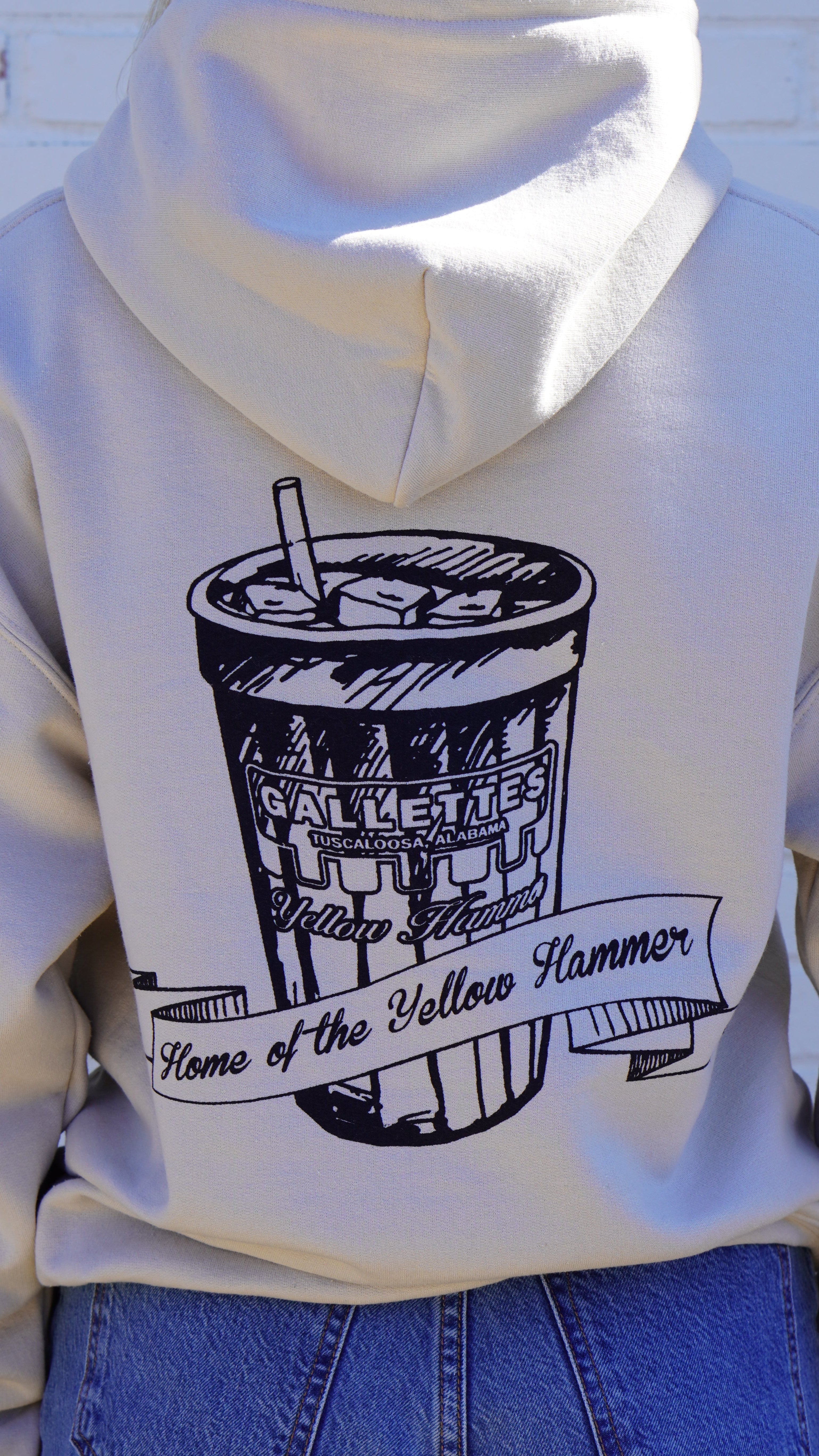 Gallettes Tan Hoodie with an illustration of a yellow hammer drink with a sash that reads “home of the yellow hammer”