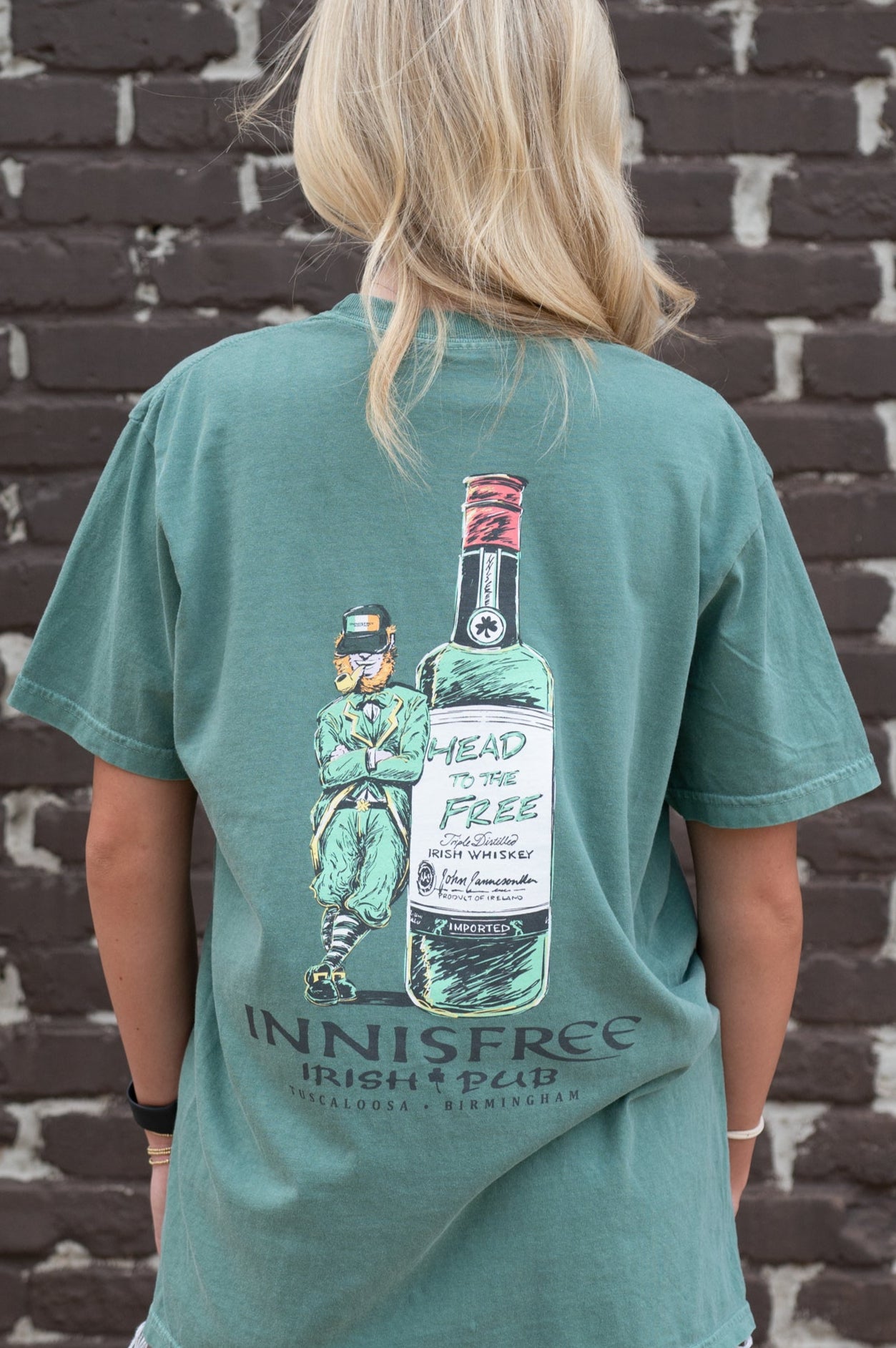 Innisfree Green T-Shirt with a hand-drawn design featuring a leprechaun leaning against a bottle and the text 'INNISFREE Irish Pub' on the back. 