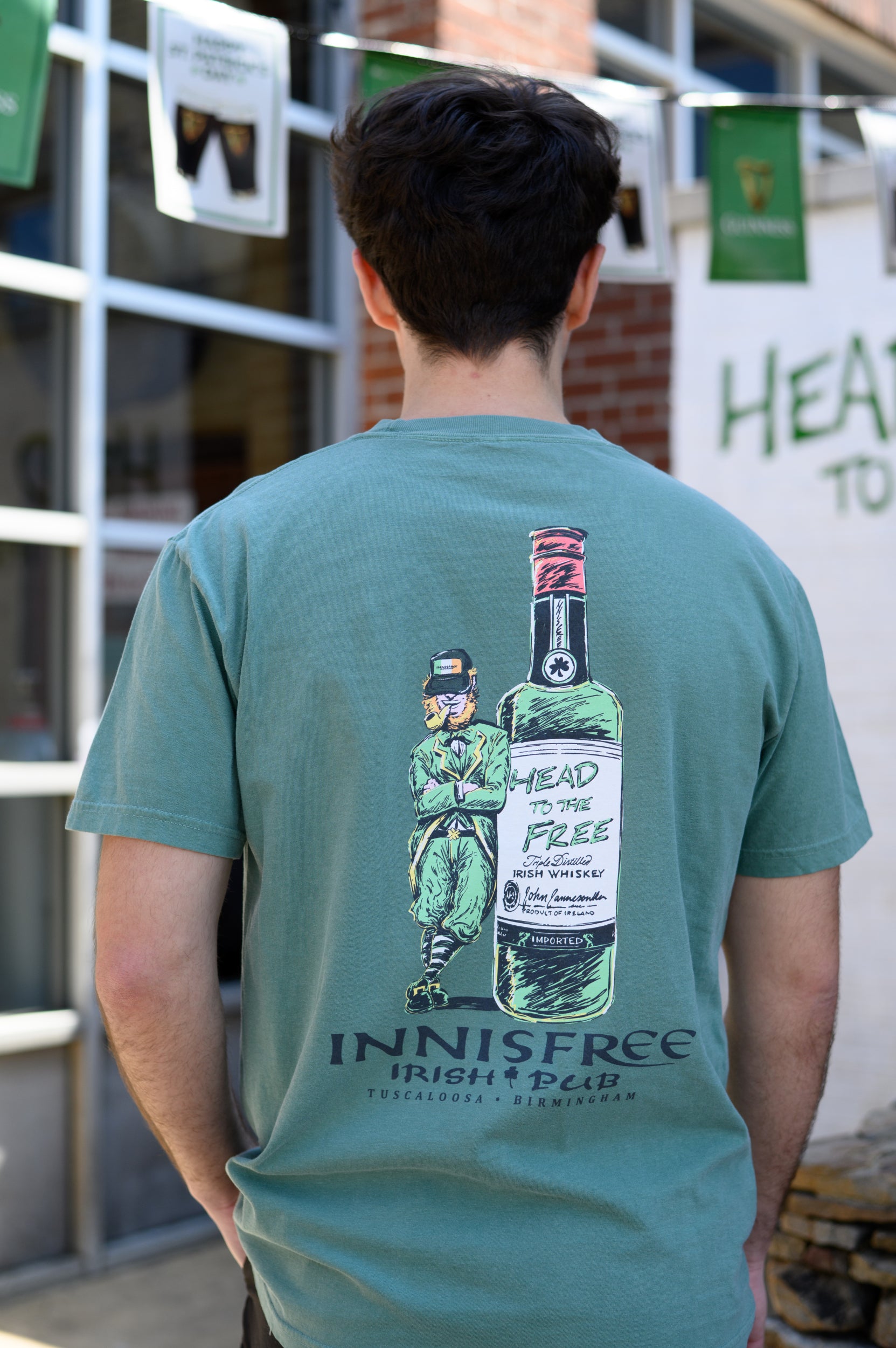 Innisfree Green T-Shirt with a hand-drawn design featuring a leprechaun leaning against a bottle and the text 'INNISFREE Irish Pub' on the back.