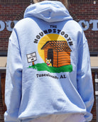 The Houndstooth Light Blue Hoodie with Black text "The Houndstooth" above an image of a corgi standing outside of a dog house