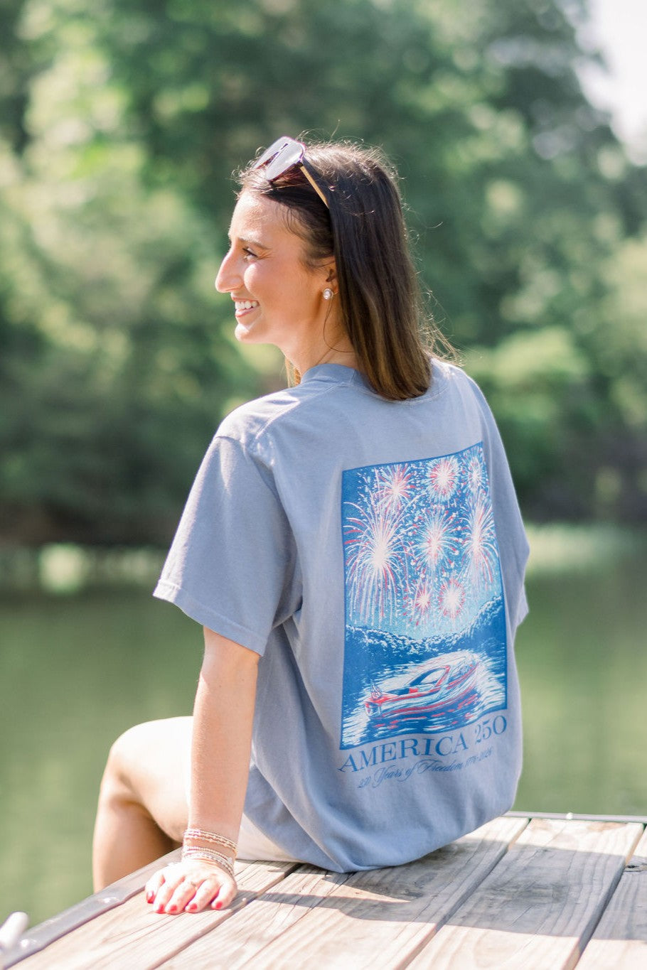 America 250 Blue Jean T-Shirt with impressionist style art of a boat on the lake while fireworks explode above, and text “America 250”