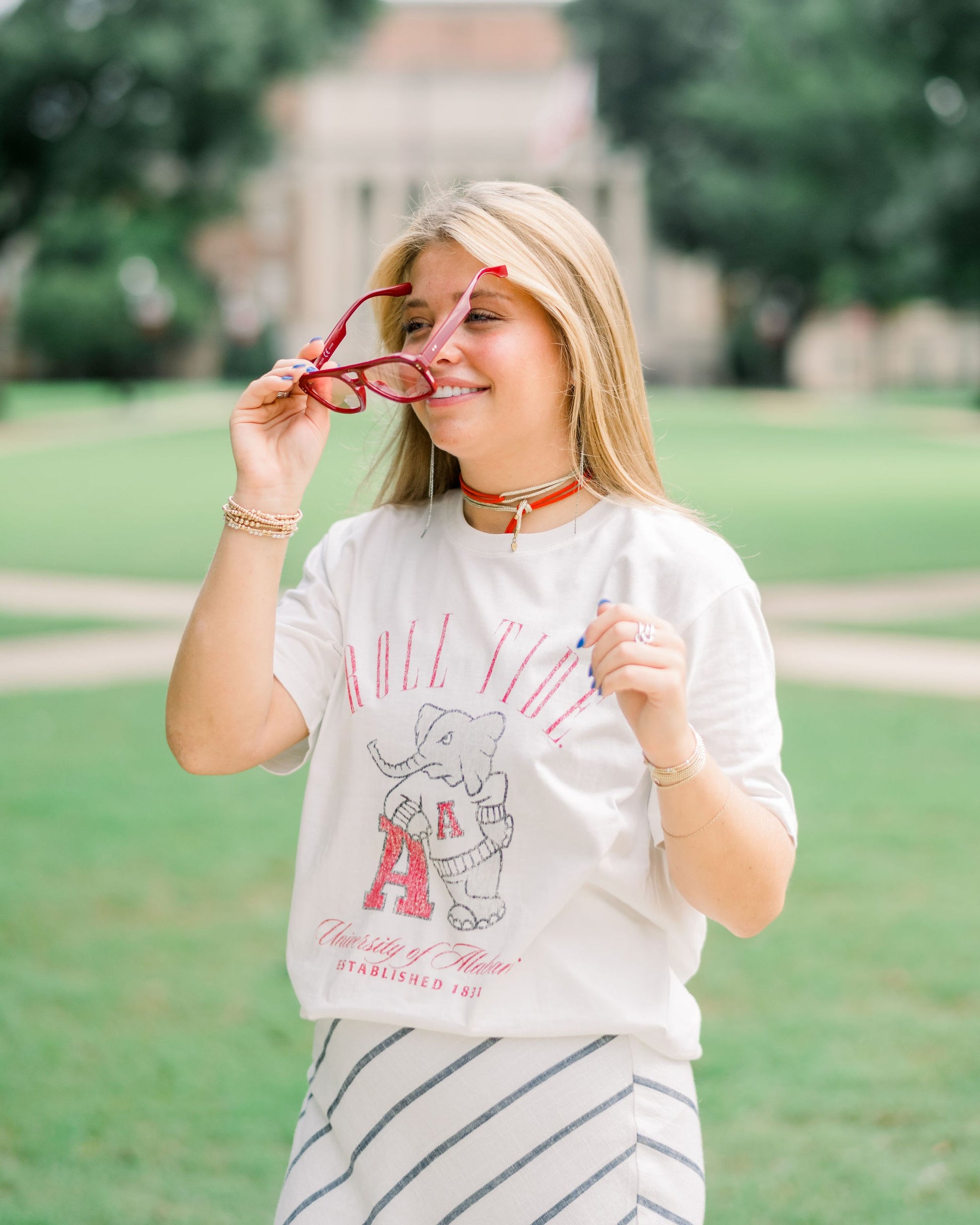 University of Alabama Ivory T-Shirt with Red text “Roll Tide” above an image of Big Al leaning on a Black A