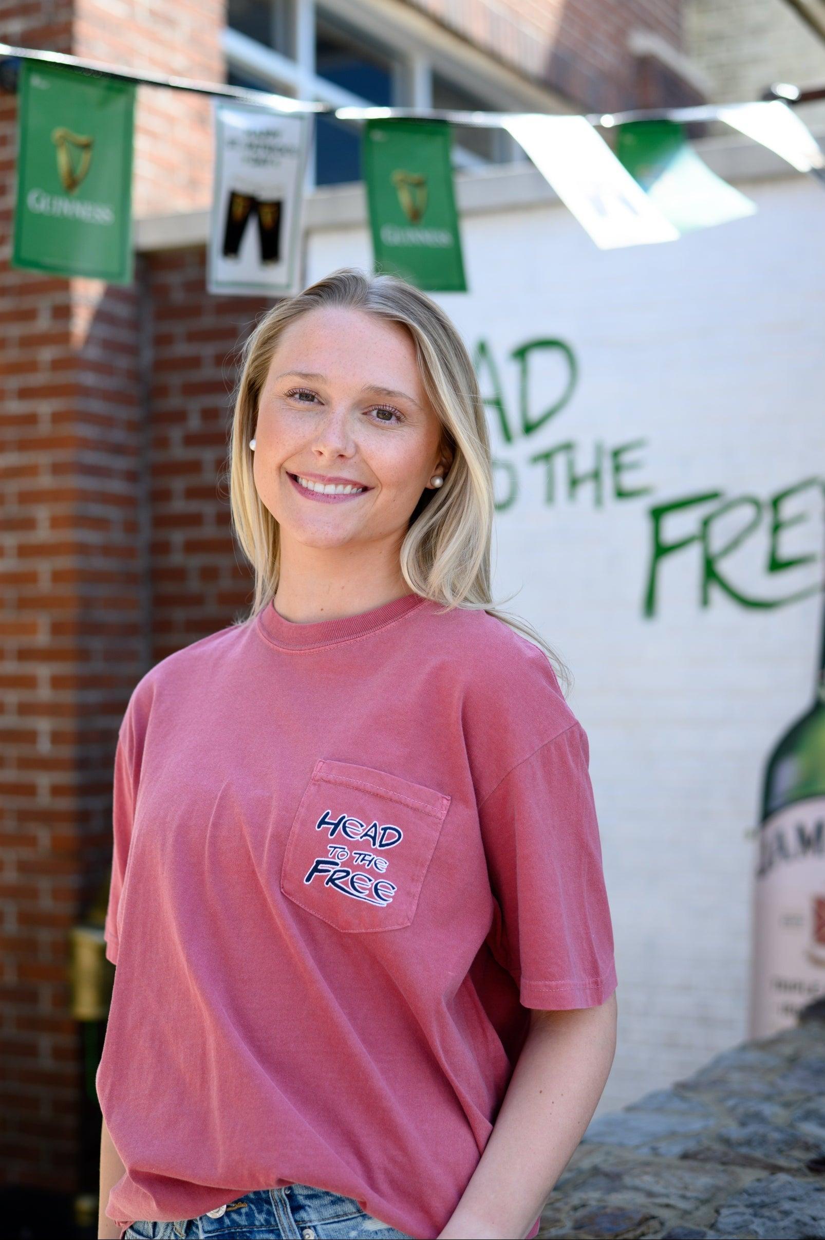 Innisfree Red Lucky Leprechaun T-Shirt with Black text “Head To The Free” on the front pocket