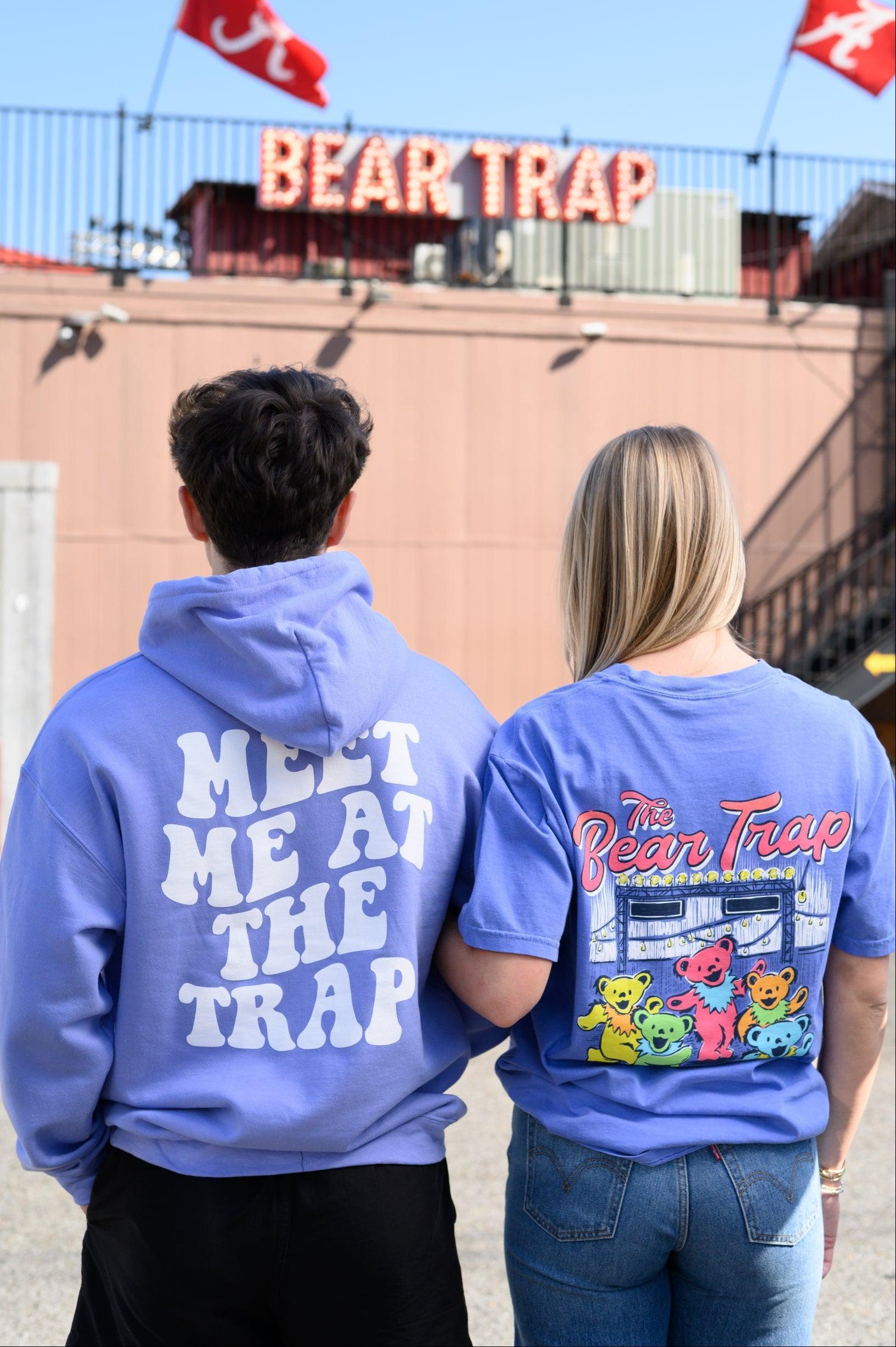 Two people wearing blue hoodies and t-shirts with 'Bear Trap' branding in front of a the Bear Trap Building