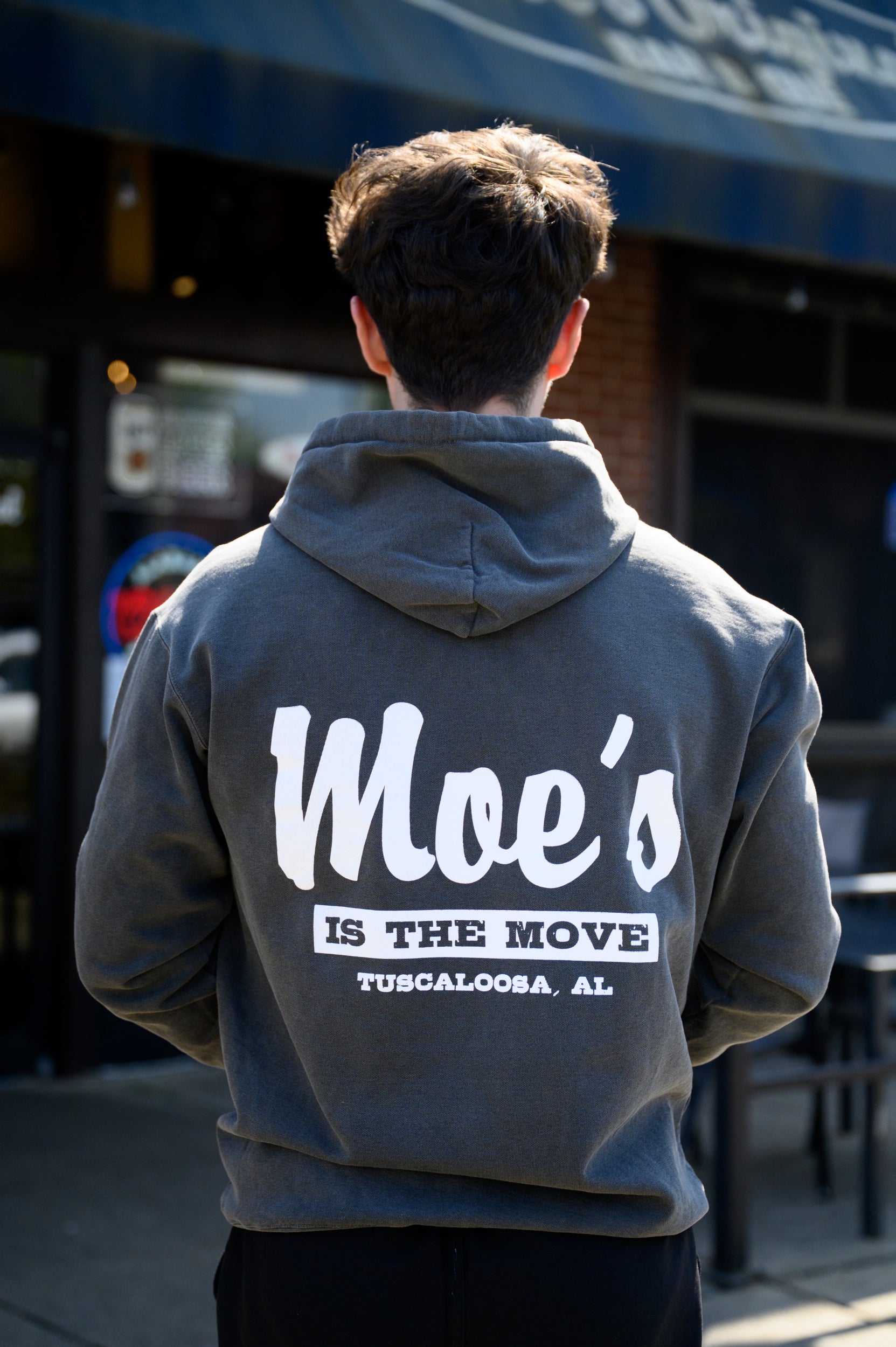 Moe's Dark Grey Hoodie with White text "Moe's” and Grey text in a White Block, “Is The Move" printed on the back