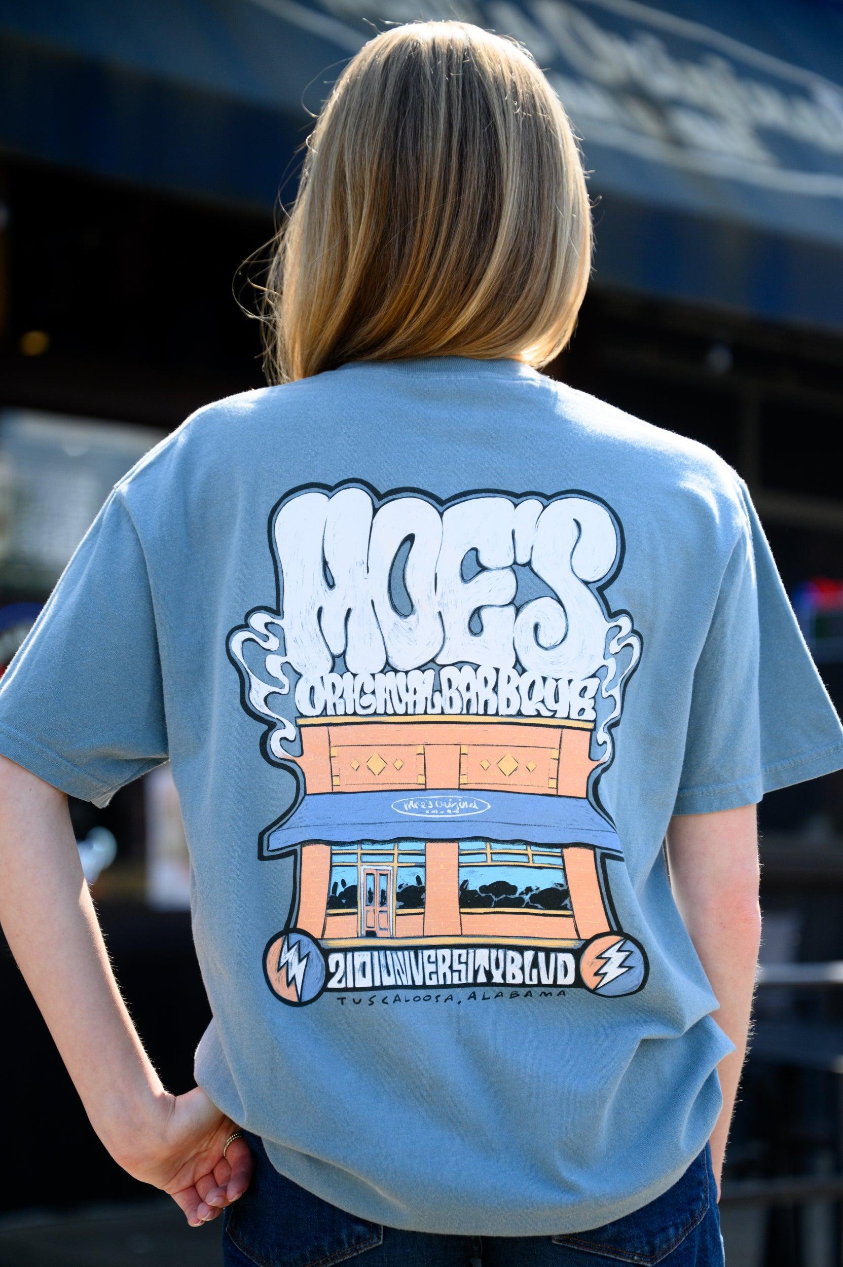 Moe's Dusty Blue T-Shirt with White text "Moe's Original Barbeque" above an illustration of the Moe’s BBQ Building