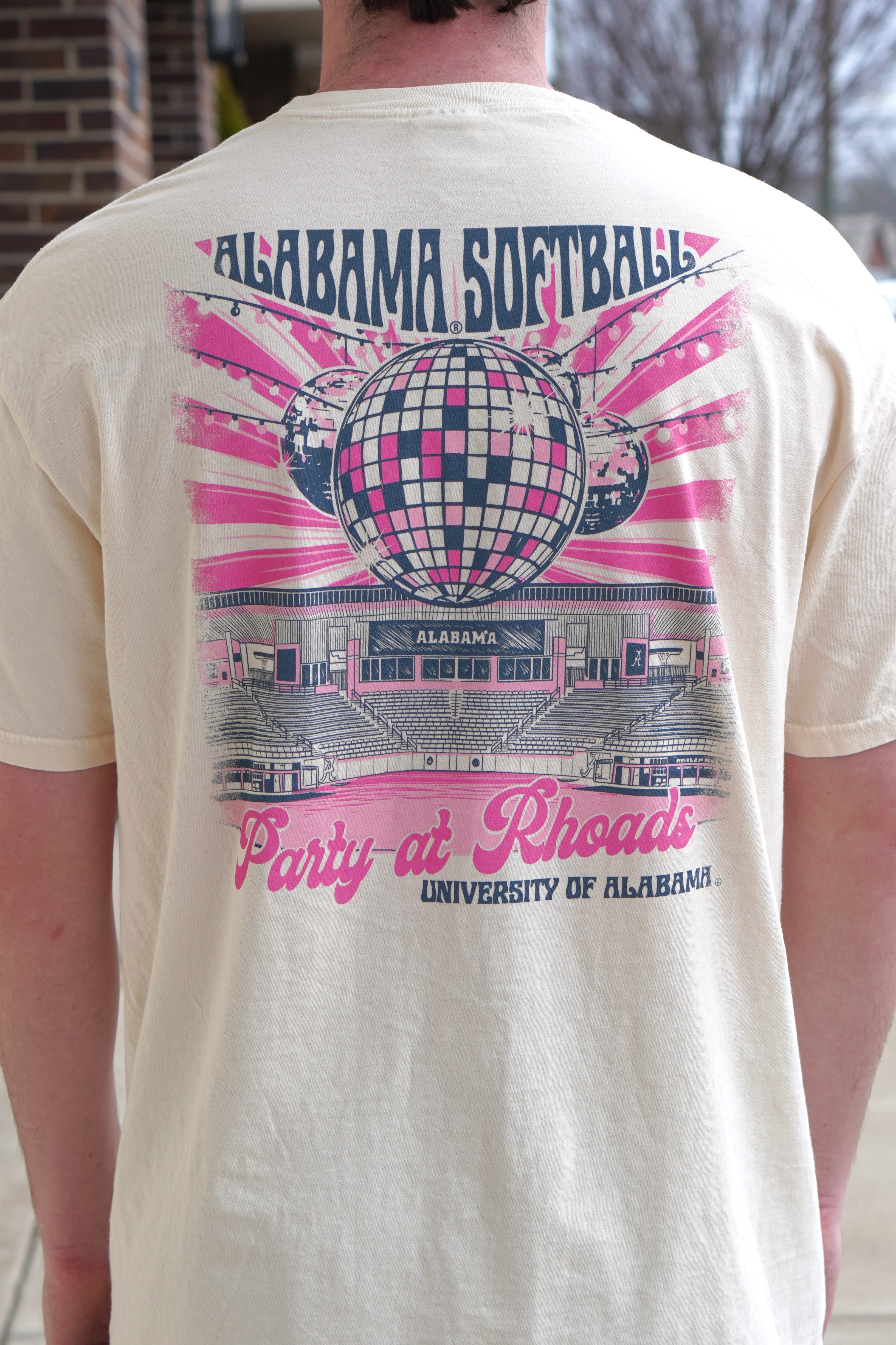 University of Alabama Ivory Ladies' T-Shirt with a hand-drawn design featuring Rhoads Stadium, disco balls, and the color pink, related to the Alabama Softball team.