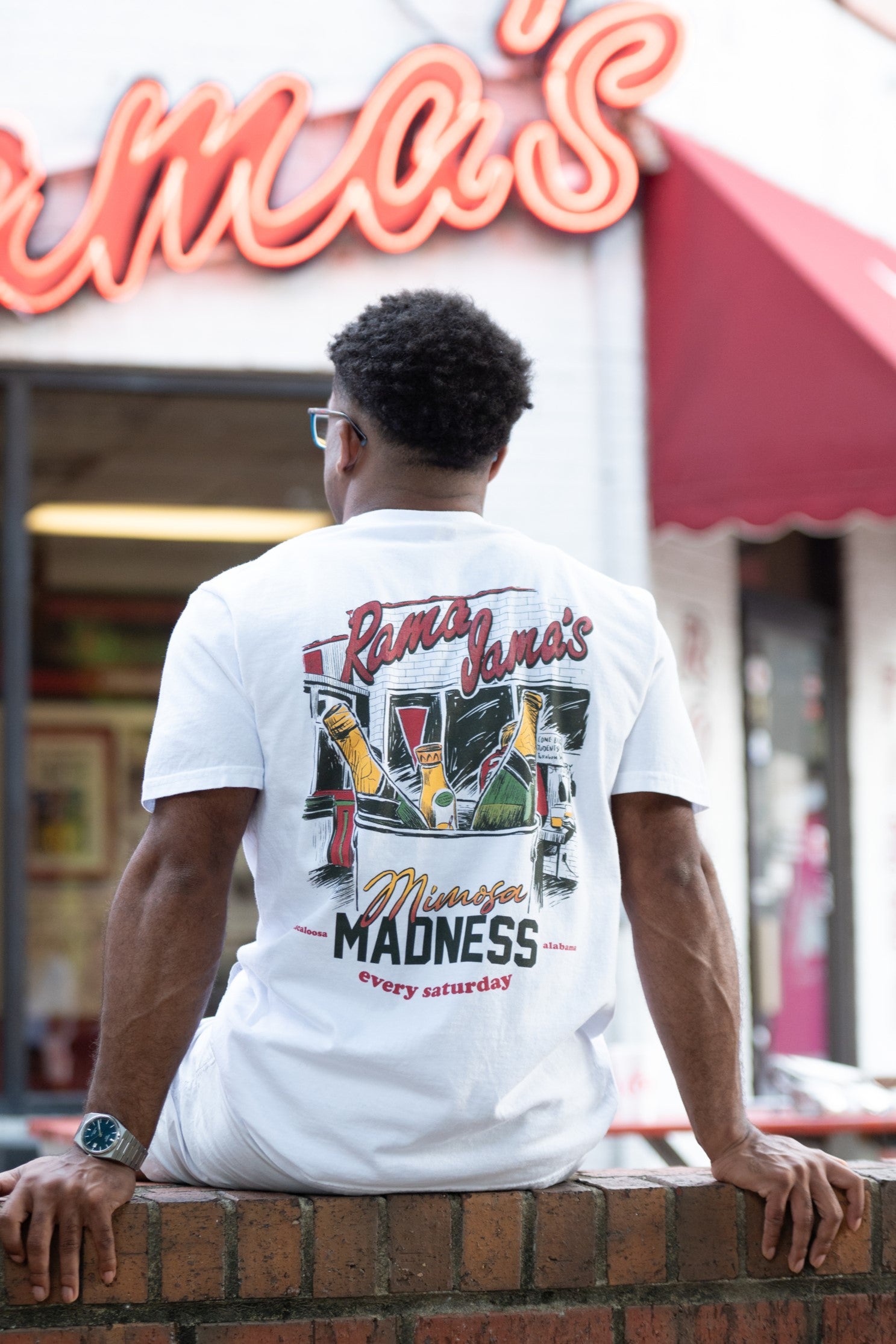 Rama Jama's White Mimosa Madness T-Shirt with an image of an ice bucket with three glass bottles inside and text "Mimosa Madness"