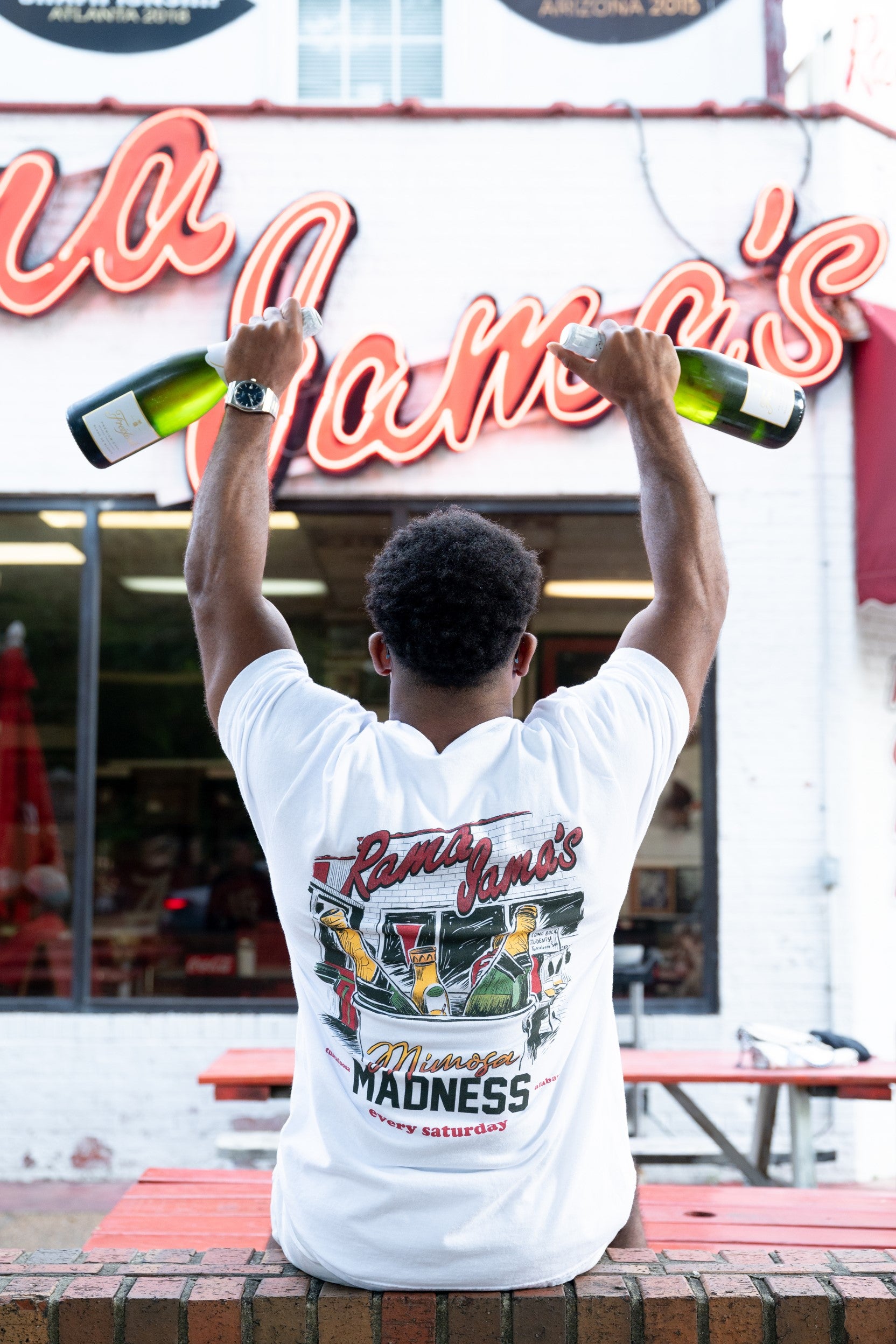 Rama Jama's White Mimosa Madness T-Shirt with an image of an ice bucket with three glass bottles inside and text "Mimosa Madness"