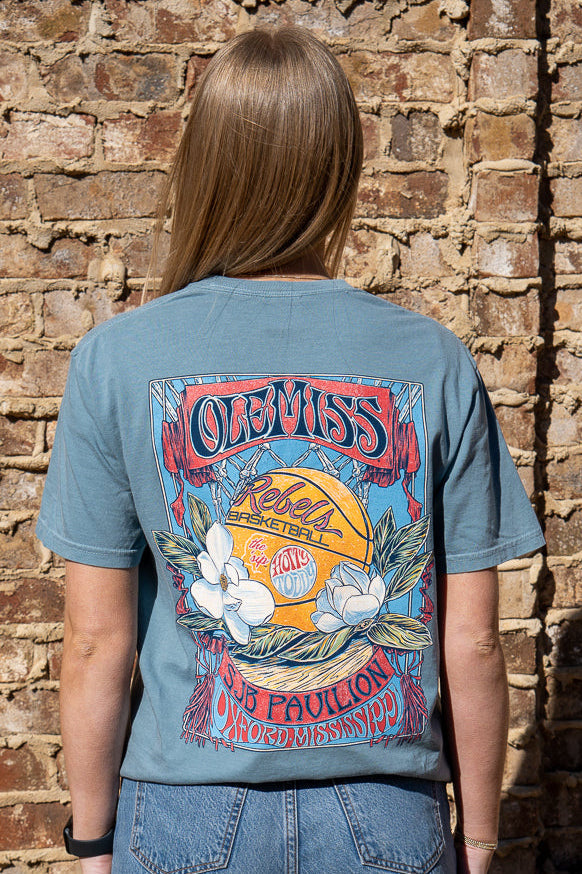 Ole Miss Dusty Light Blue T-Shirt with a basketball card style design featuring a basketball with magnolia flowers in between text “Ole Miss” and “SJB Pavillion”