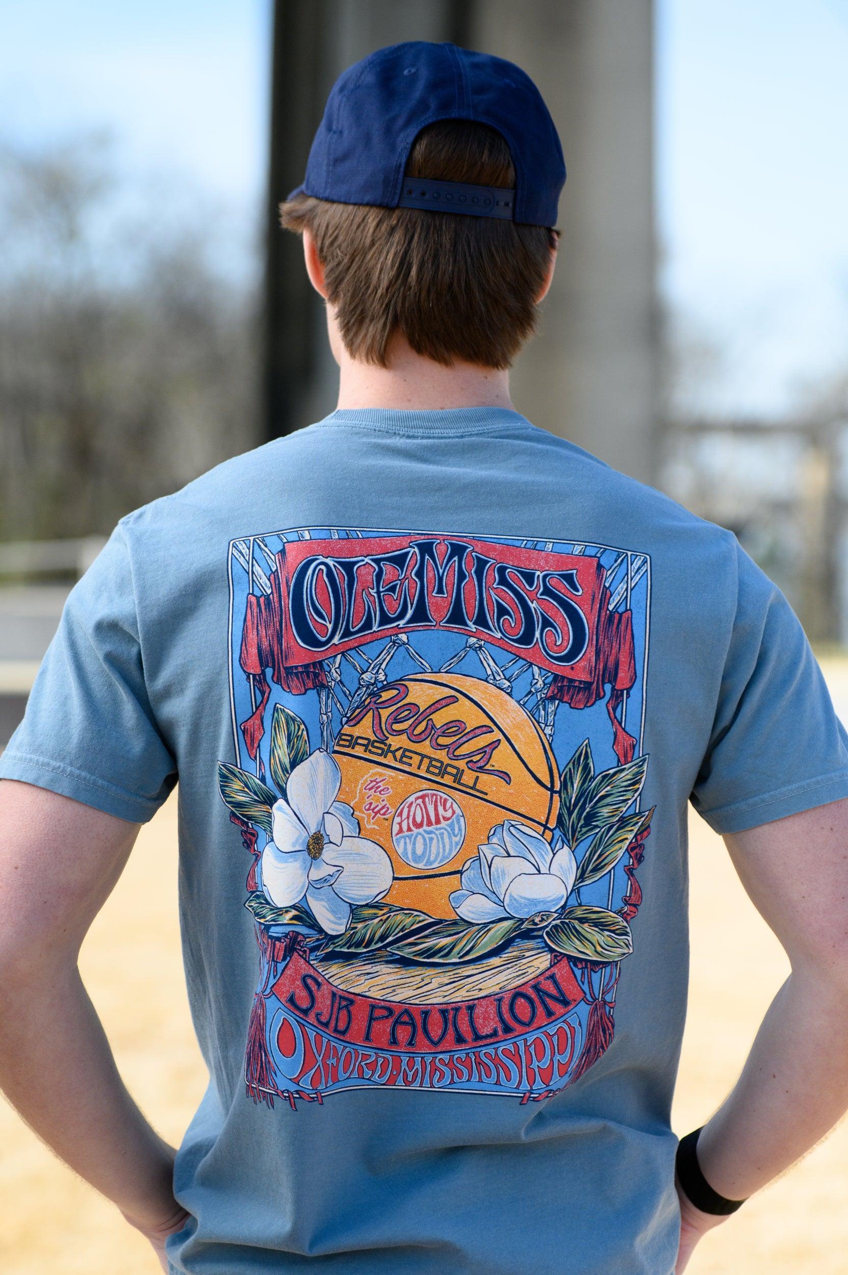 Ole Miss Dusty Light Blue T-Shirt with a basketball card style design featuring a basketball with magnolia flowers in between text “Ole Miss” and “SJB Pavilion”