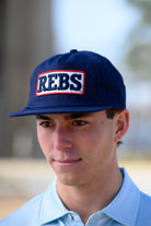 Ole Miss Navy Snapback Hat featuring a White patch with Navy “REBS” embroidery
