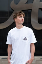 University of Alabama White T-shirt with a Script A brand folding chair that has a red flannel hanging over the back and a play planning board leaning against it. Below, Black text reading “The Tide is Rising”