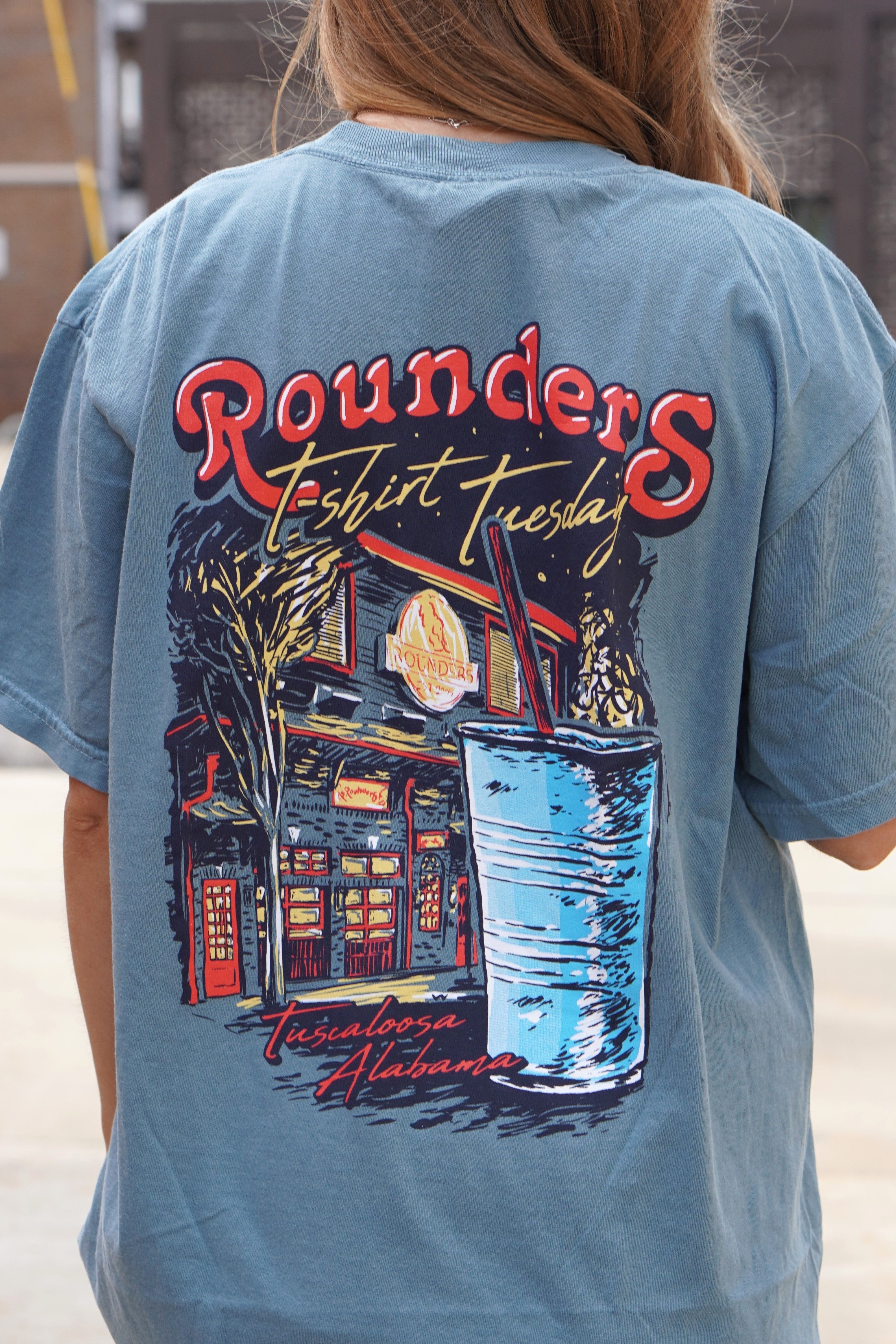 Rounders Blue T-Shirt with text "Rounders T-shirt Tuesday" above the Rounders Building and a Blue drink