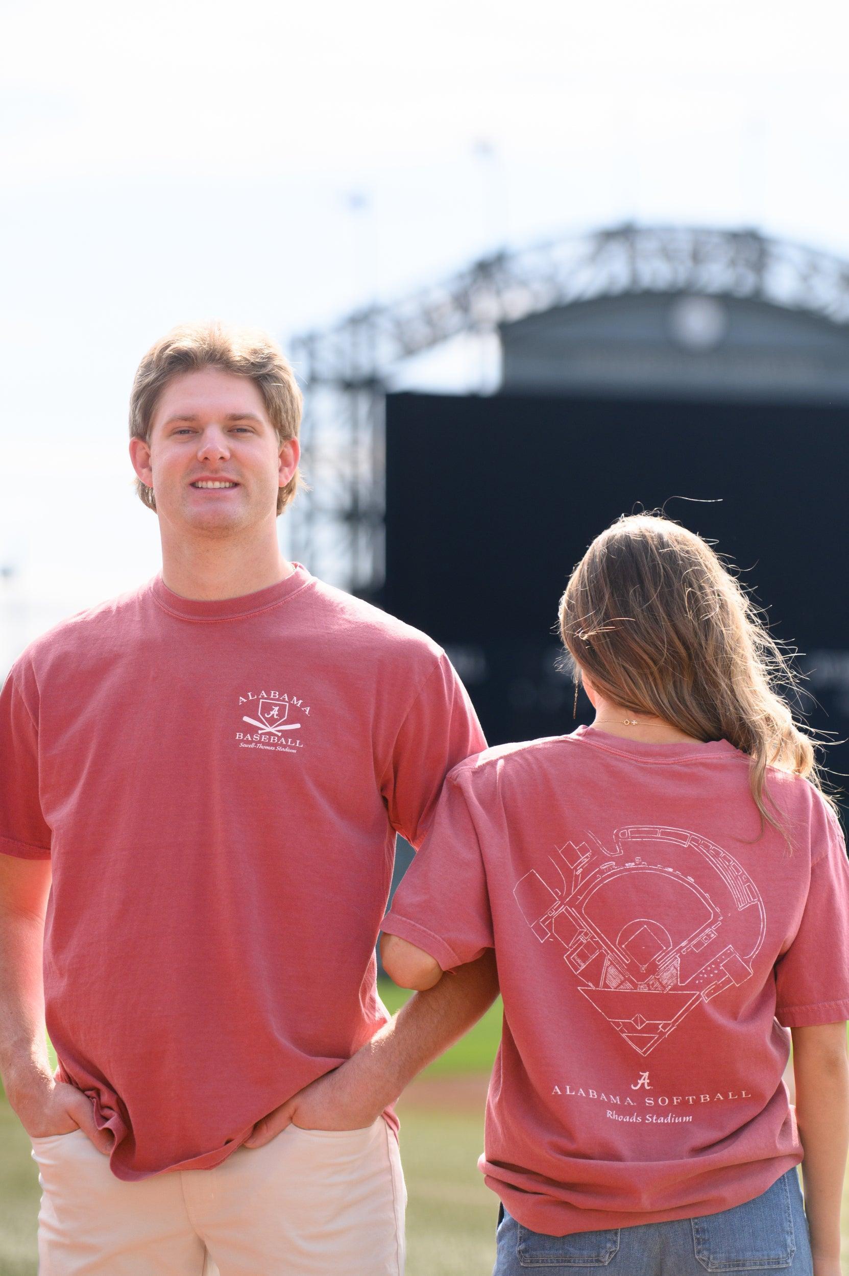 Two people wearing red t-shirts with a logo, standing in front of a stage.