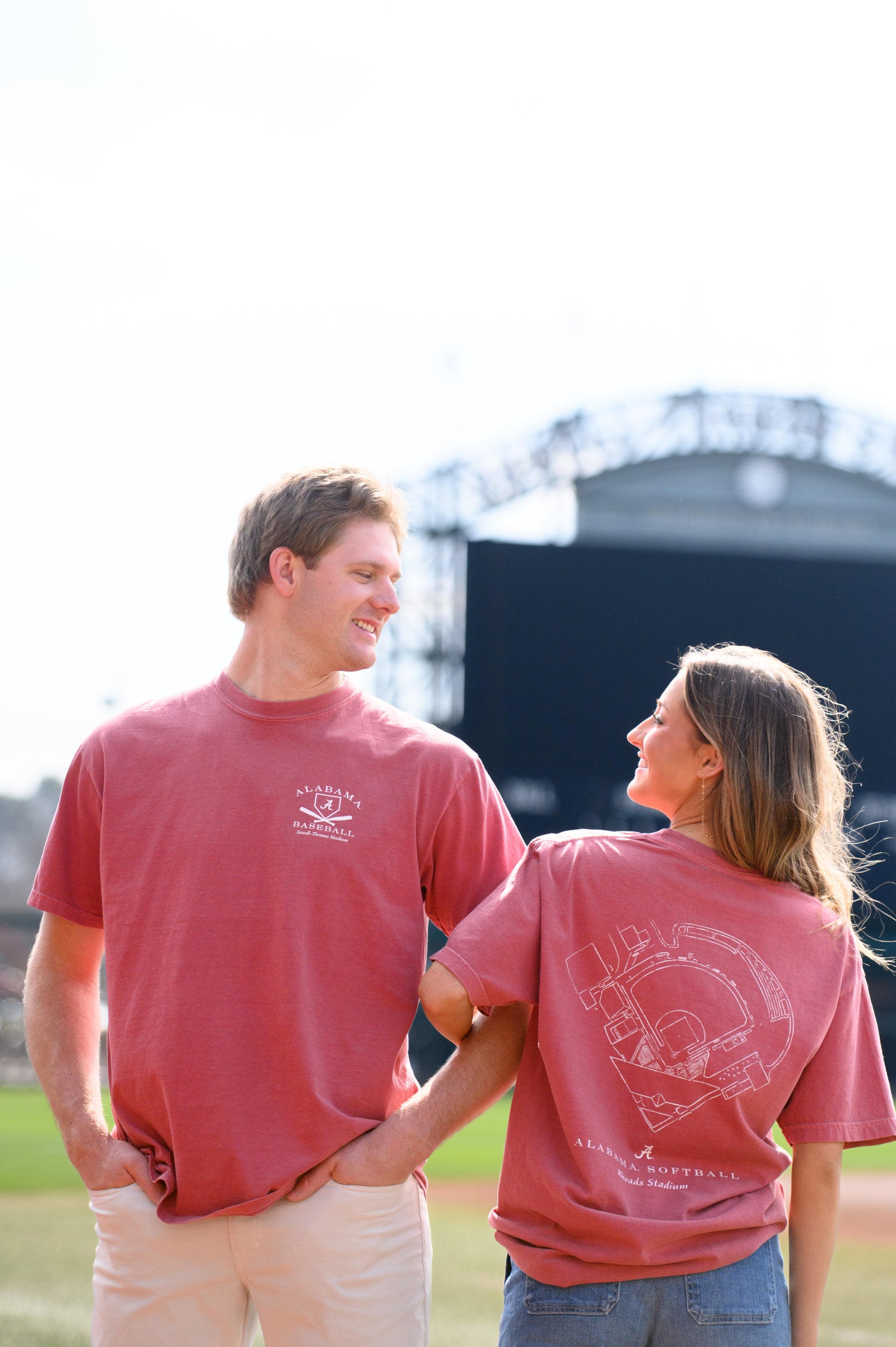 Two people wearing red t-shirts with logos, standing outdoors.
