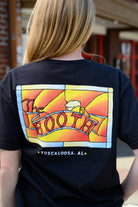 The Booth Black T-Shirt with a stained-glass style graphic featuring a banner with text “The Booth” and a mug of beer