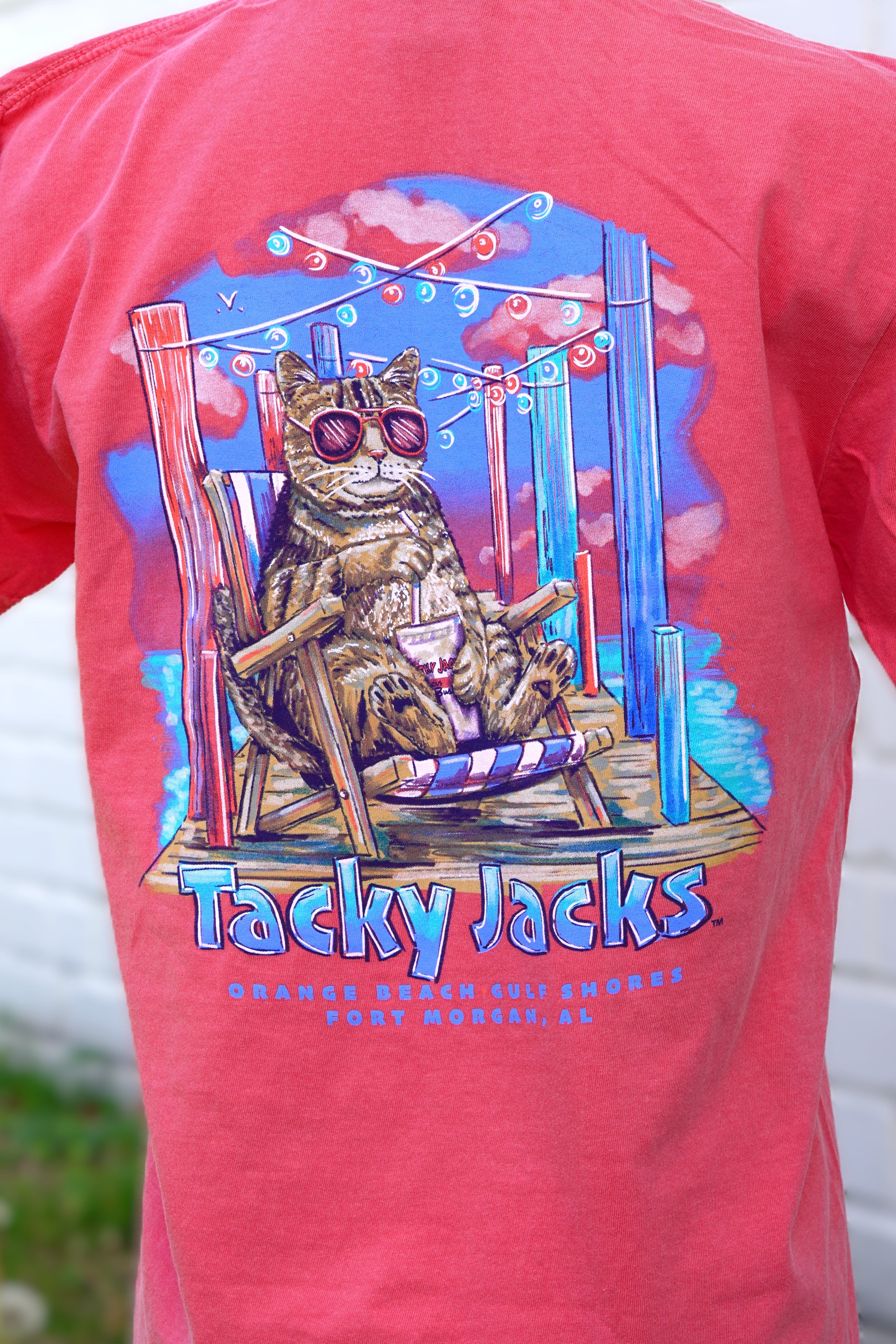 Tacky Jacks Watermelon T-Shirt with an image of a brown tabby cat wearing pink sunglasses and enjoying a drink on a pier above text "Tacky Jacks" 