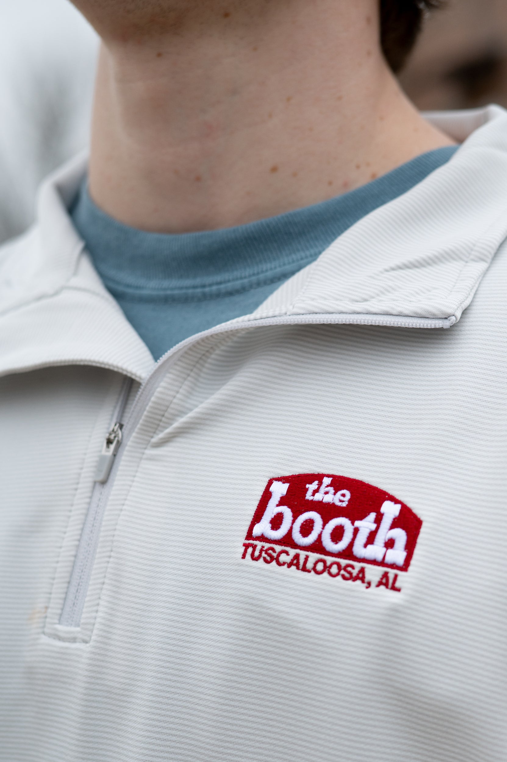 The Booth Light Blue Stripe Men’s Pullover with a Red The Booth Logo embroidered on the chest