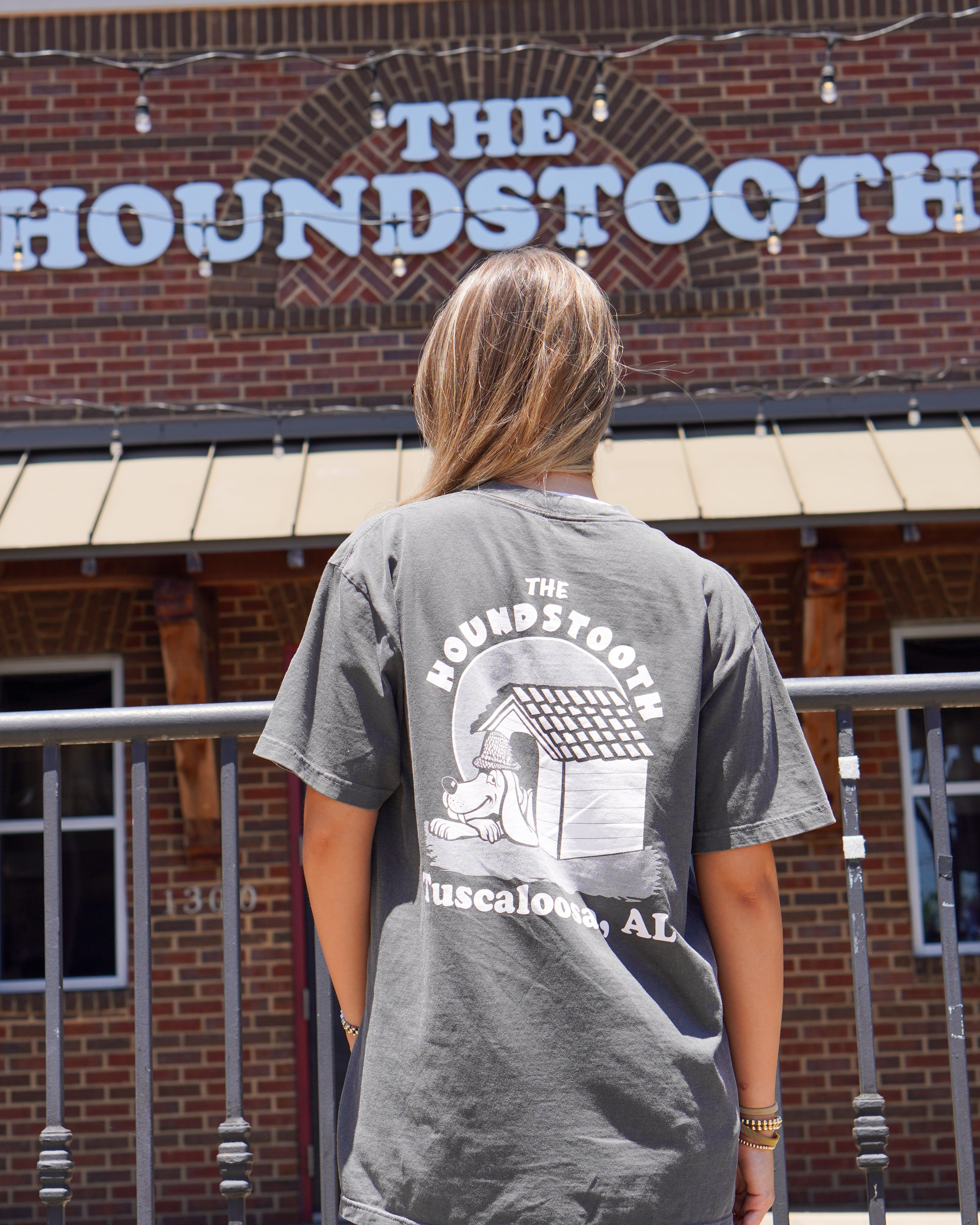 The Houndstooth Dark Grey T-Shirt with White text "The Houndstooth" above an image of a Beagle laying inside of a doghouse