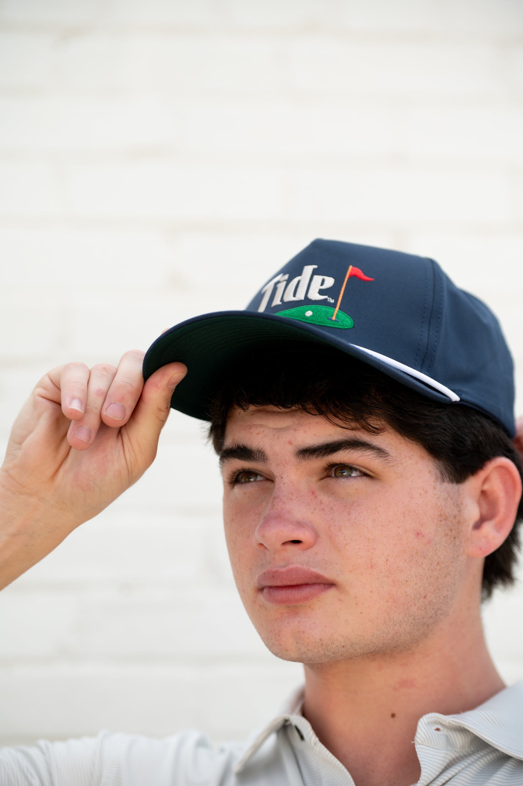 University of Alabama Navy Hat with a White Rope and White text “Tide” above an image of a golf hole