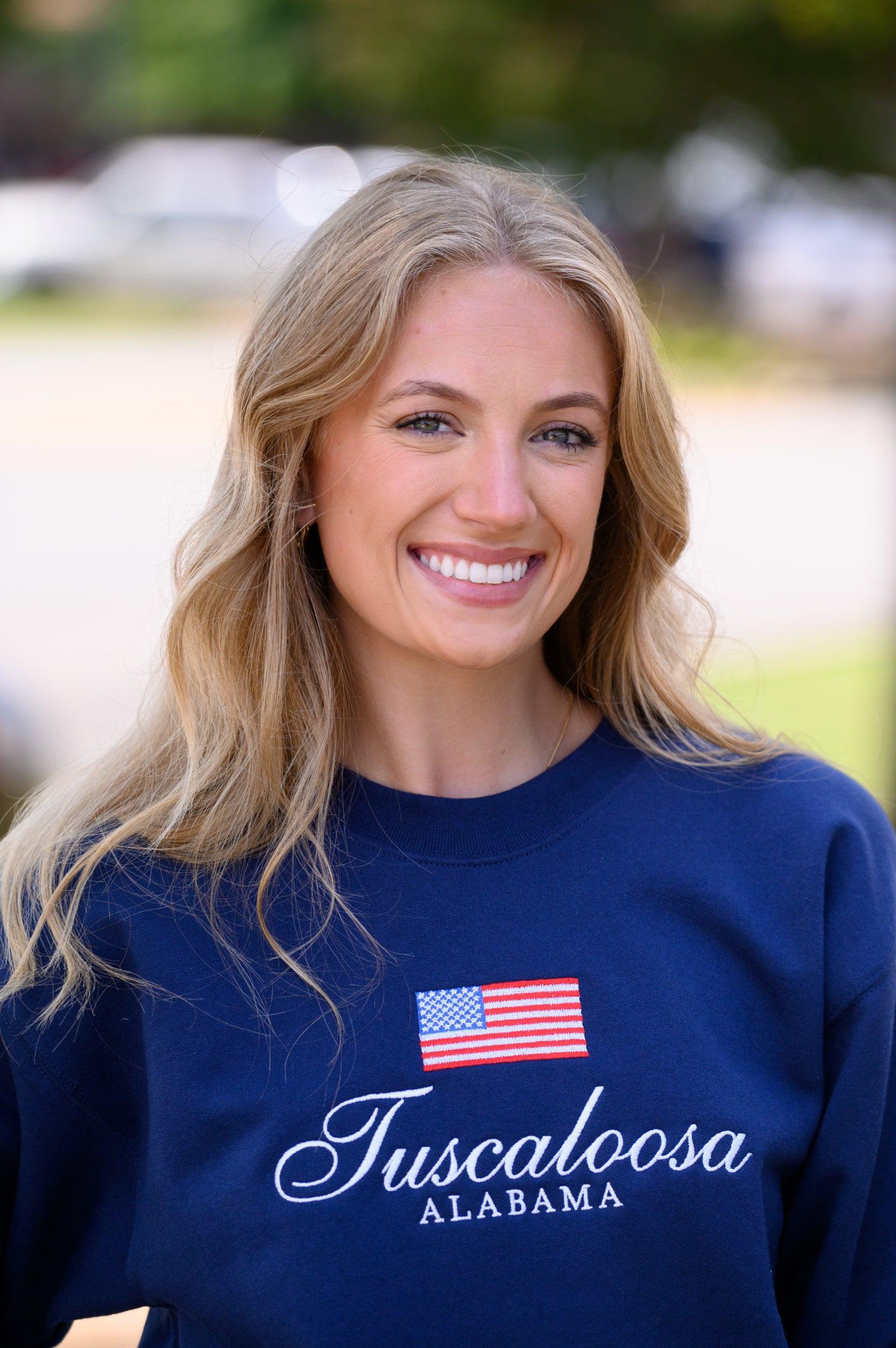 Local Merch Navy Crewneck with an embroidered American Flag above White embroidered text “Tuscaloosa Alabama”