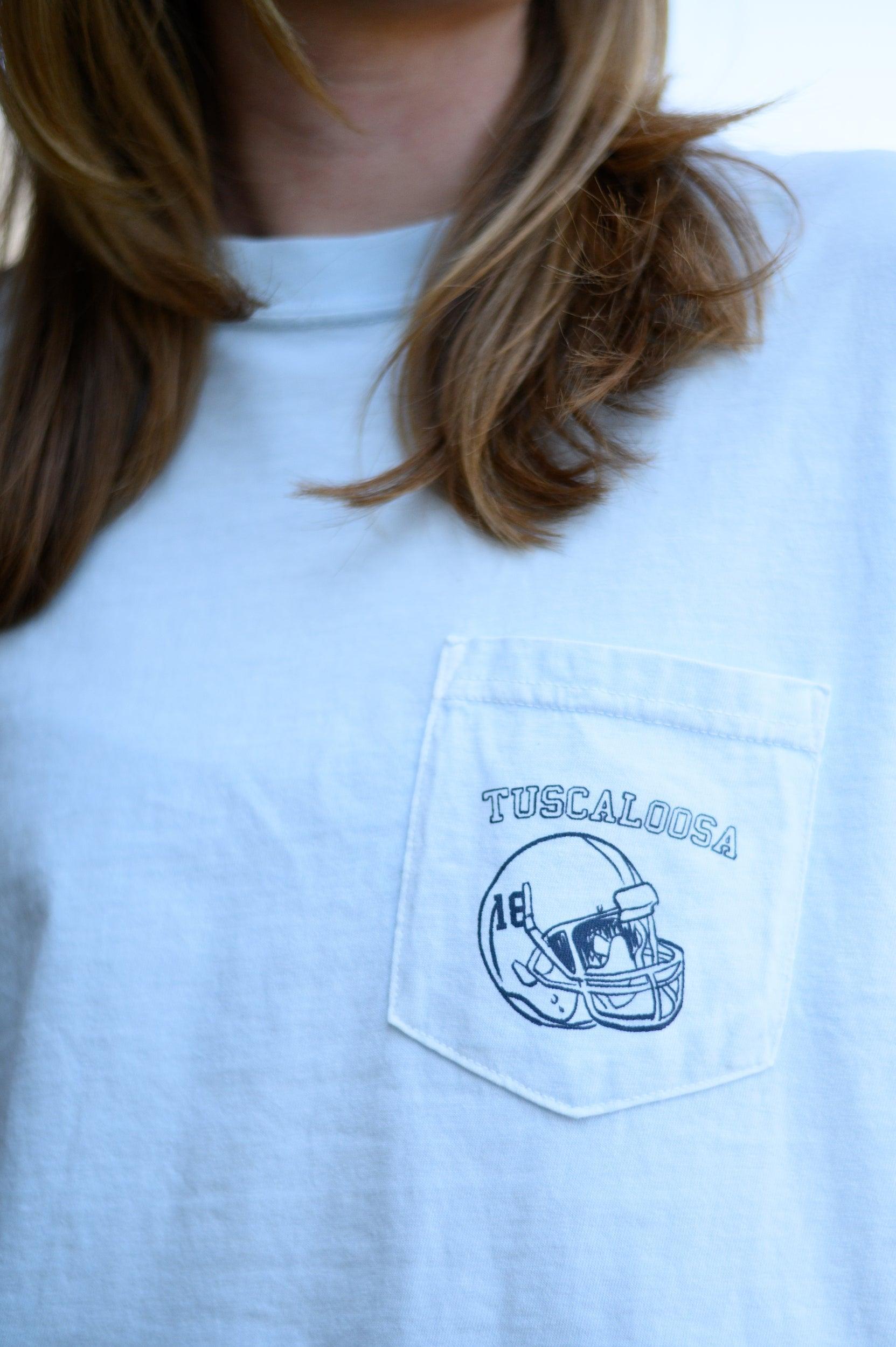 Local Merch Light Blue T-Shirt with a front pocket design featuring a football helmet and text “Tuscaloosa”