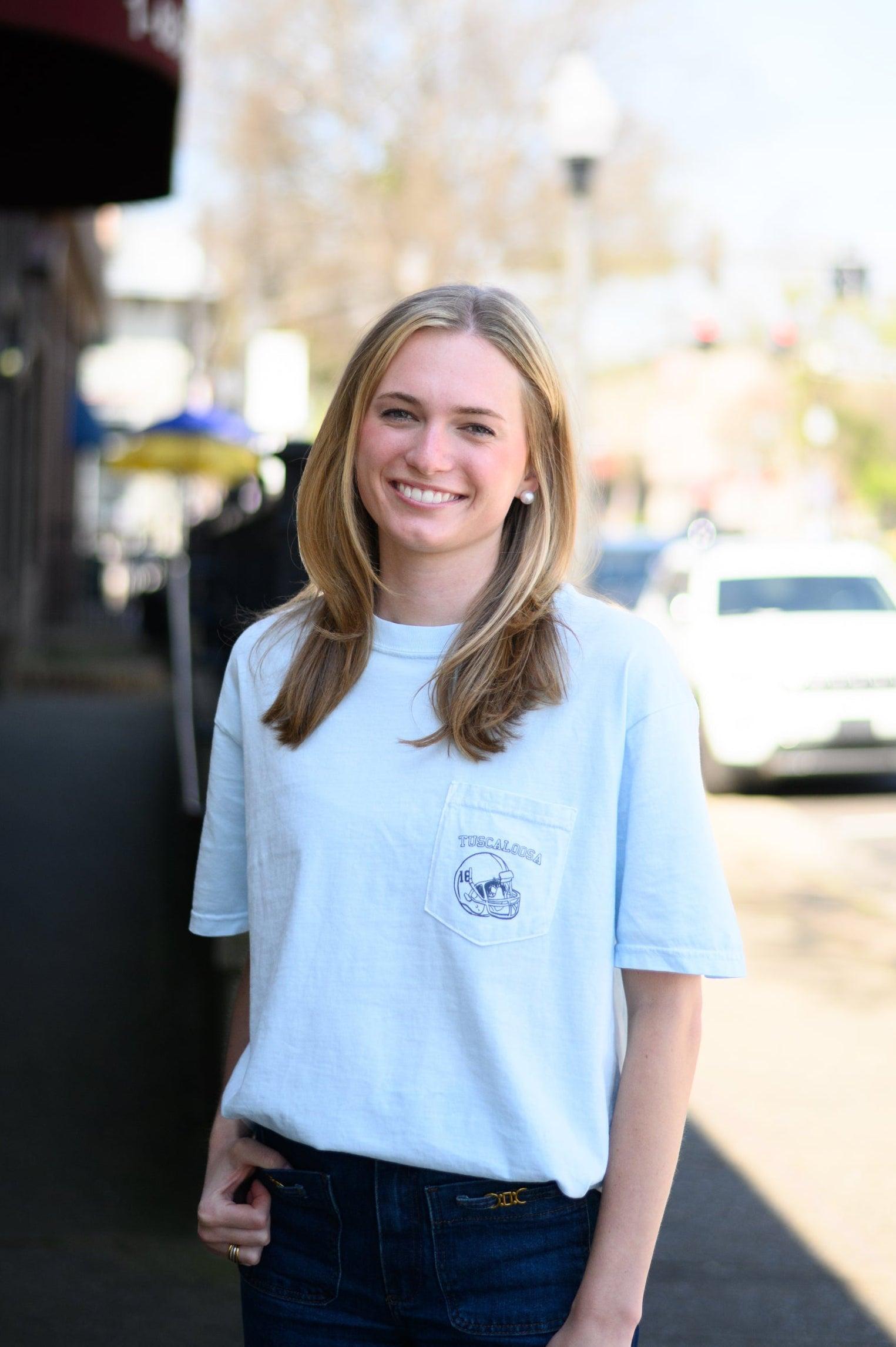 Local Merch Light Blue T-Shirt with a front pocket design featuring a football helmet and text “Tuscaloosa”