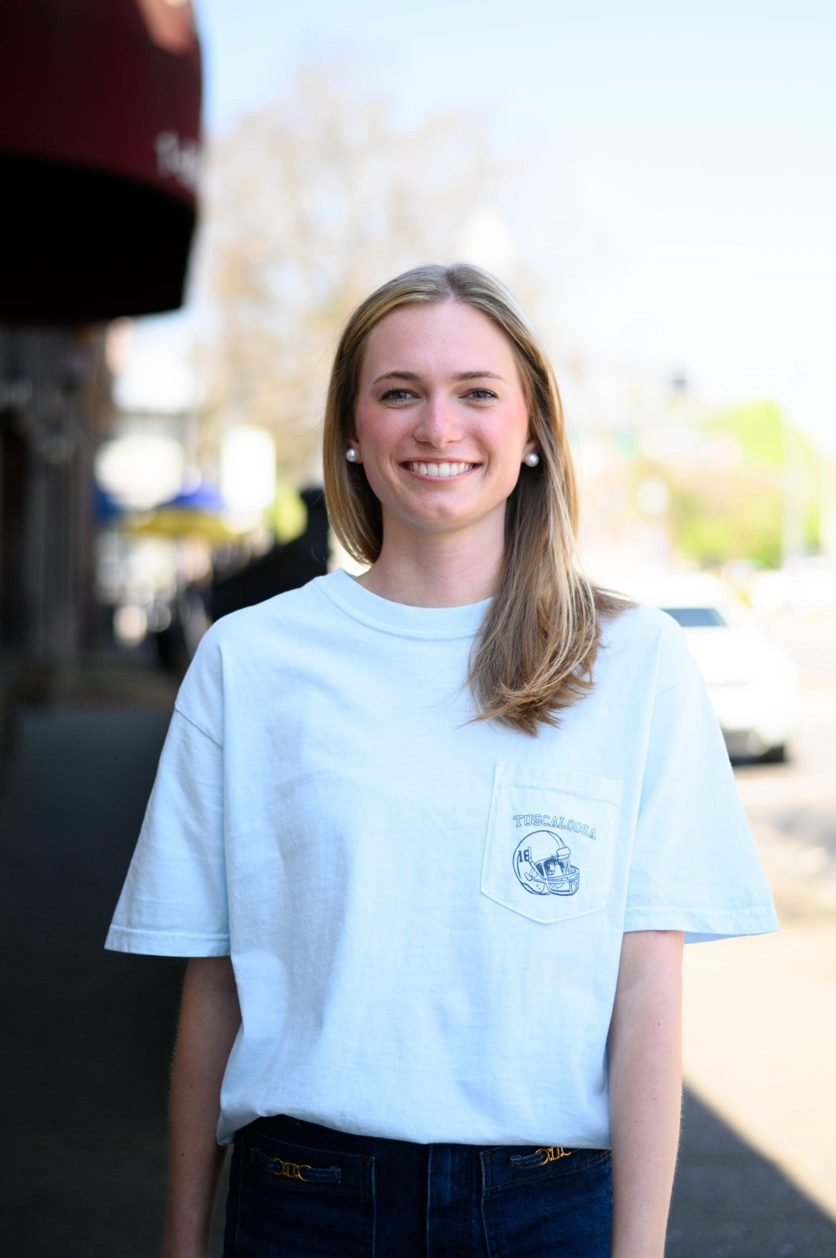Local Merch Light Blue T-Shirt with a front pocket design featuring a football helmet and text “Tuscaloosa”