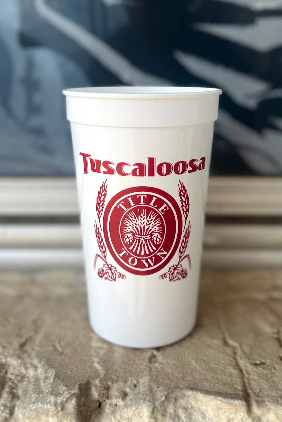 Tuscaloosa White Stadium Cup with Red text "Tuscaloosa" above the Red and White Title Town emblem, a bundle of wheat with the words "Title Town" circling it