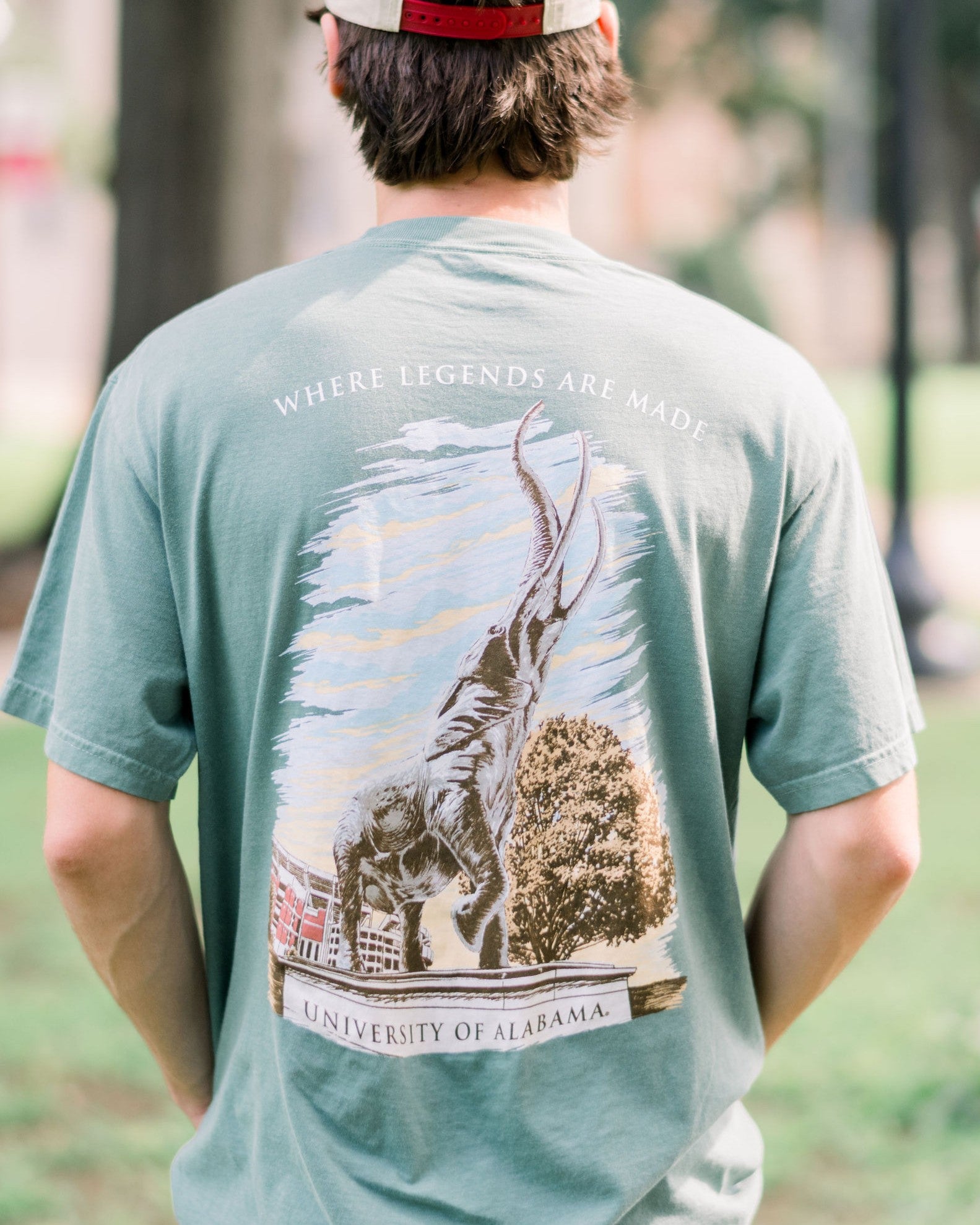 University of Alabama Green T-Shirt with an image of the Tuska Statue underneath White text "Where Legends Are Made"
