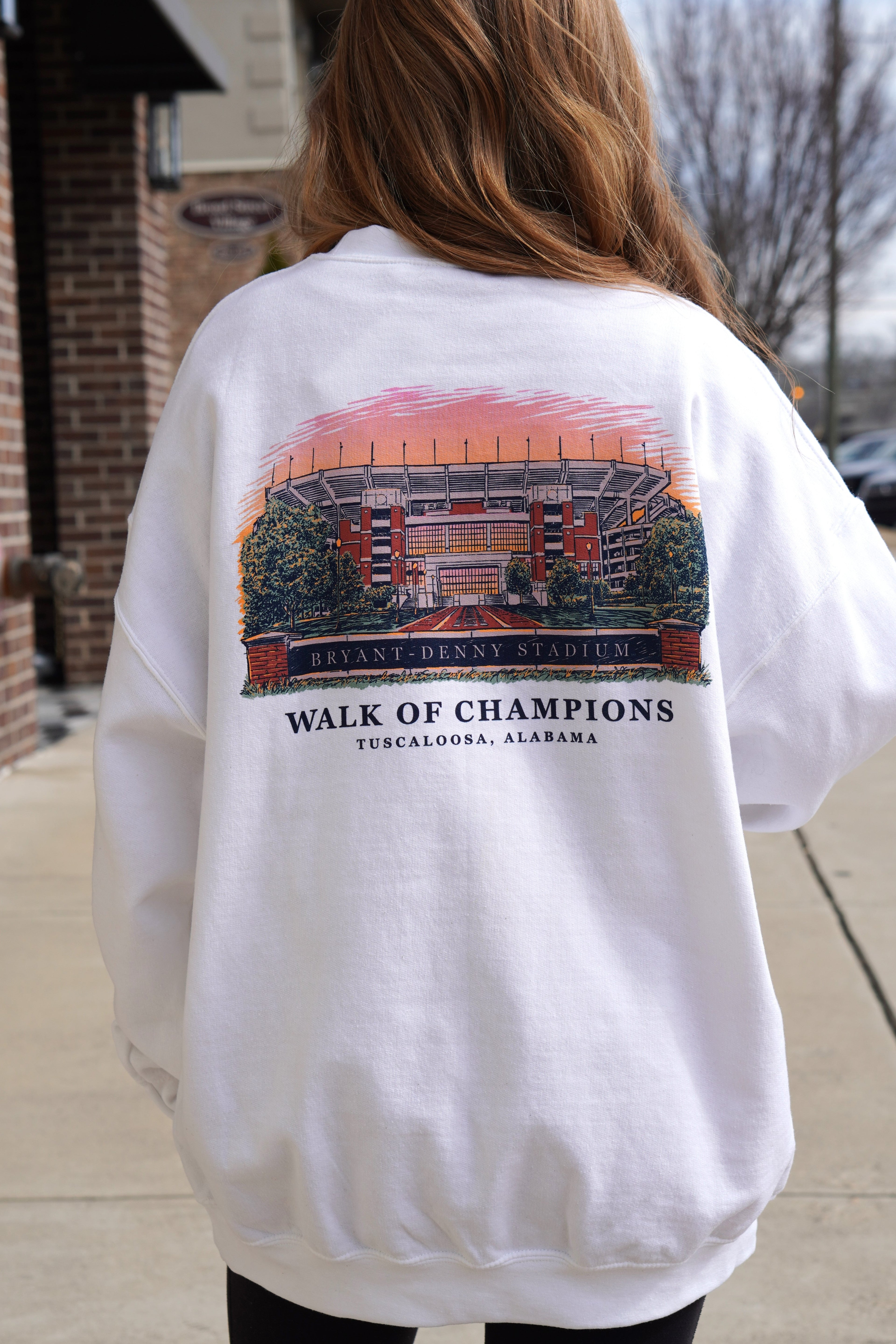 University of Alabama White Crewneck with a hand-drawn design featuring Bryant Denny Stadium and the text 'Walk of Champions - Tuscaloosa, Alabama.'.