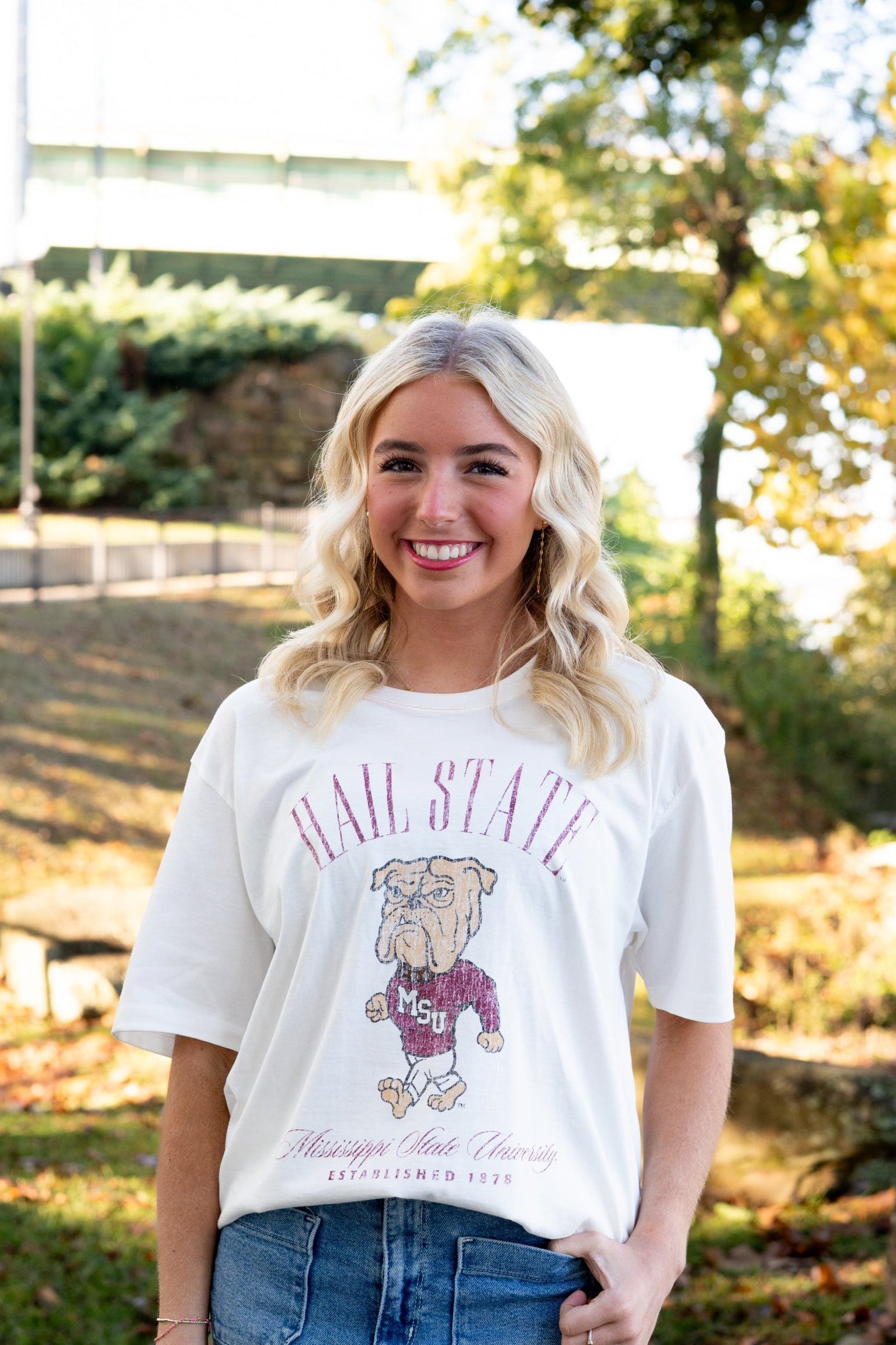 Mississippi State Ivory T-Shirt with Red text “Hail State” above an image of the Walking Bully Logo