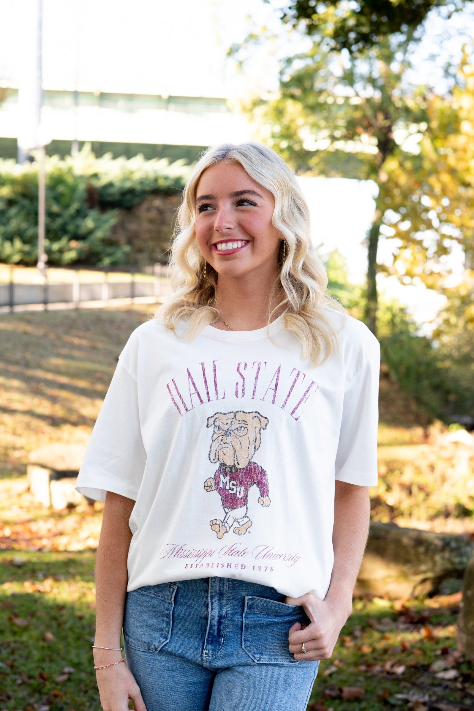 Mississippi State Ivory T-Shirt with Red text “Hail State” above an image of the Walking Bully Logo