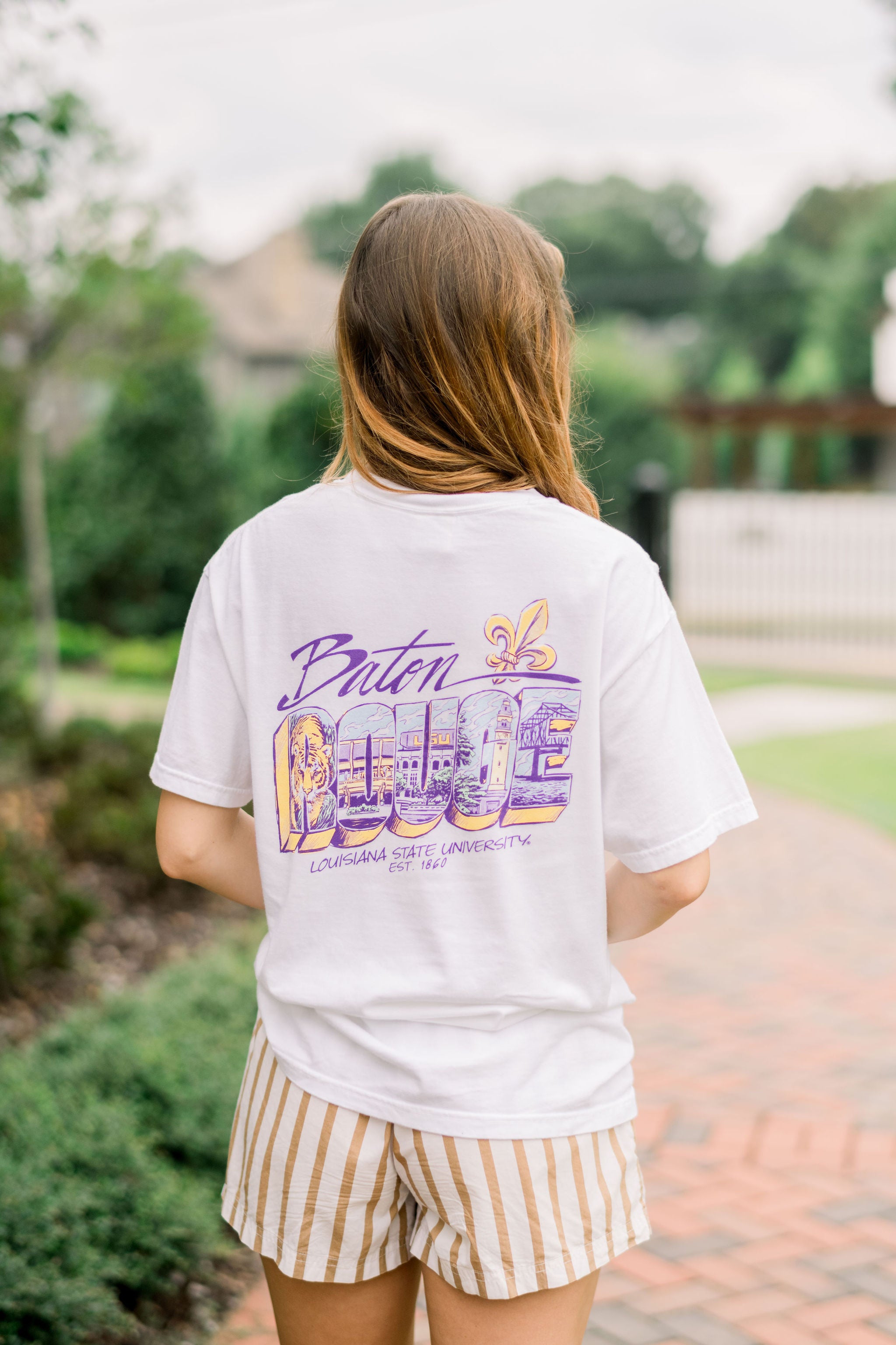 Louisiana State University White T-Shirt with postcard style text “Baton Rouge” with images of a tiger, Tiger Stadium, the Memorial Tower, and the New Bridge