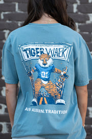 Auburn University Aubie Tiger Walk Ice Blue Comfort Colors T-Shirt with an image of Aubie the Tiger leading a parade under a banner with the text "Tiger Walk"