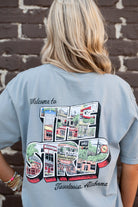 University of Alabama Grey The Strip T-Shirt with postcard style text "Welcome to THE STRIP" with "The Strip" filled with images of iconic buildings in that location