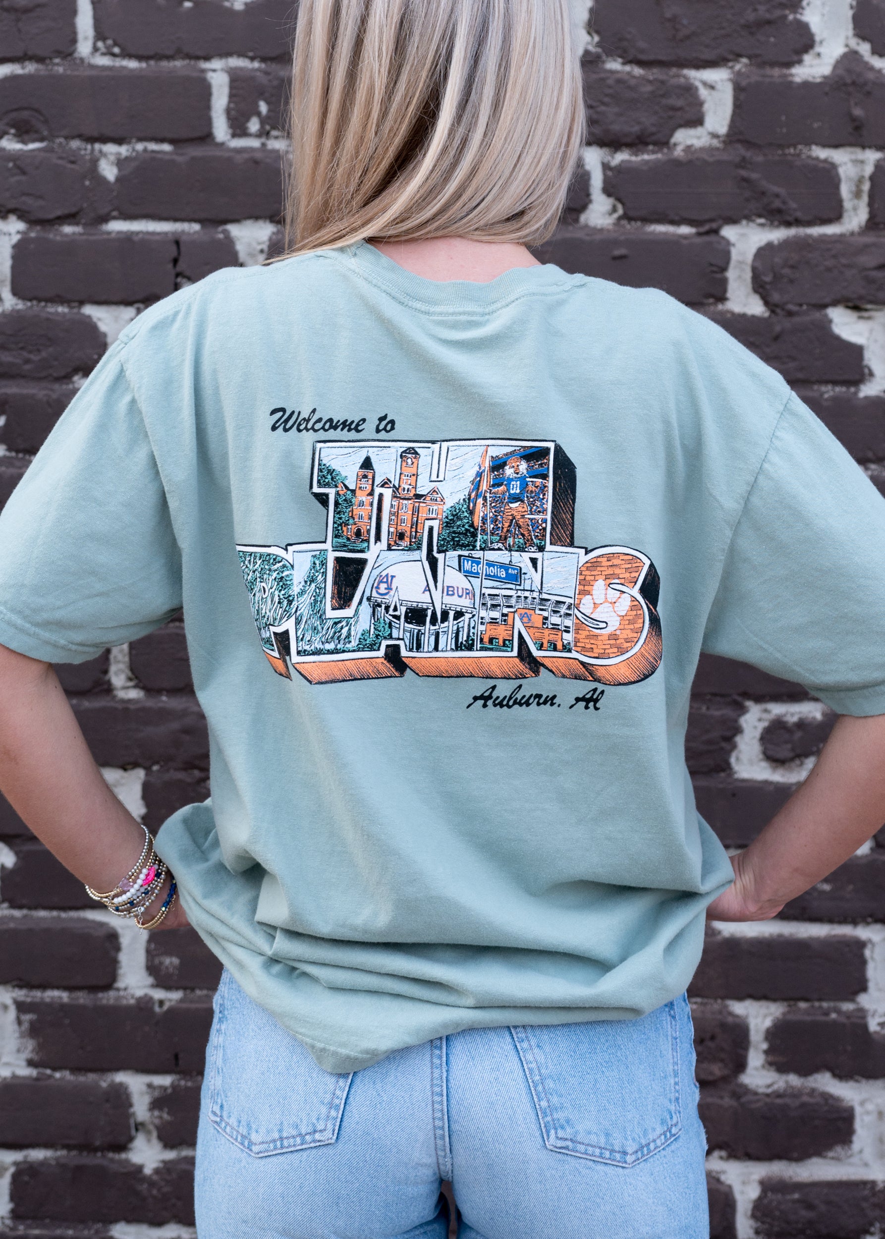Auburn University Green The Plains T-Shirt with postcard style text "Welcome to THE PLAINS" with "The Plains" filled with images of iconic buildings in that location